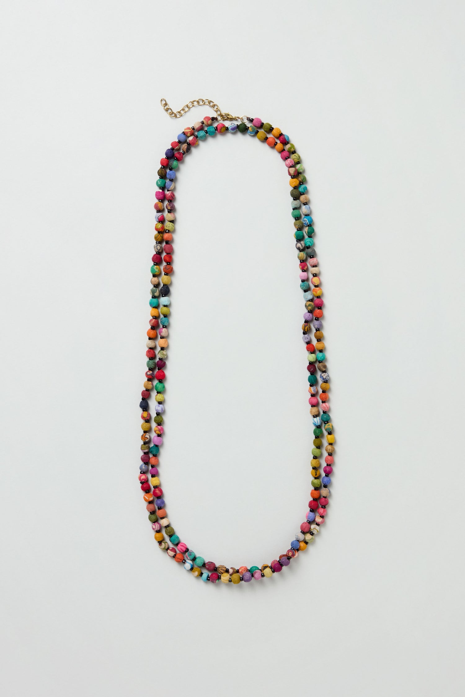 The Kantha Long Bead Spheres Necklace features handmade, small, round, multicolored beads and a gold chain clasp, displayed on a white background.