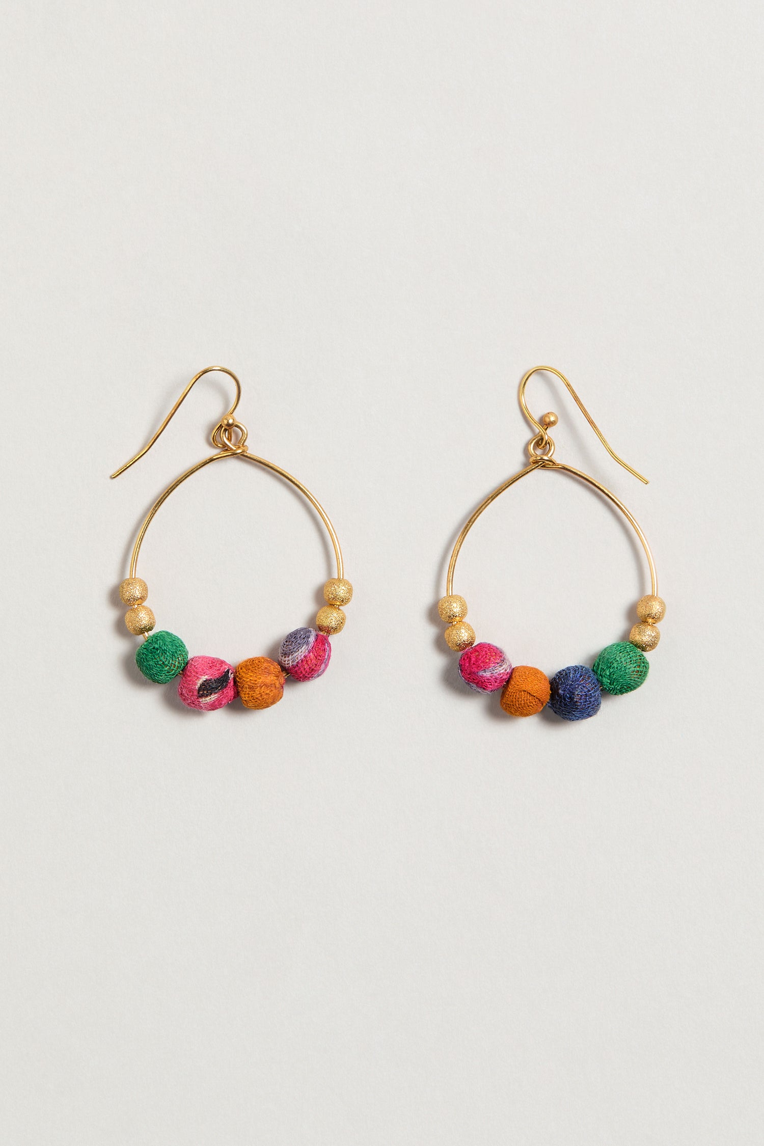 Kantha Gilded Hoop Earrings, handcrafted from recycled cotton with multicolored fabric and gold beads, are artisan hoop earrings displayed on a plain white background.