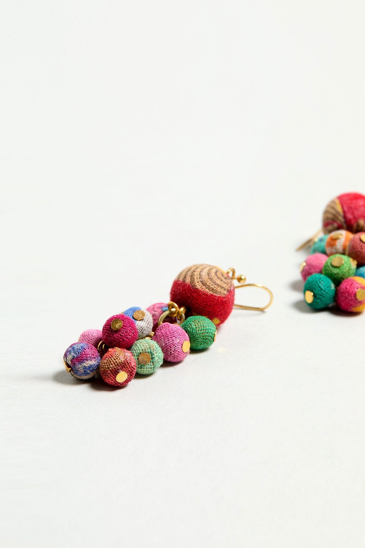 Kantha Spheres Earrings: Vibrant dangle earrings crafted from multicolored fabric beads made of repurposed textiles with gold accents, shown against a plain white background.