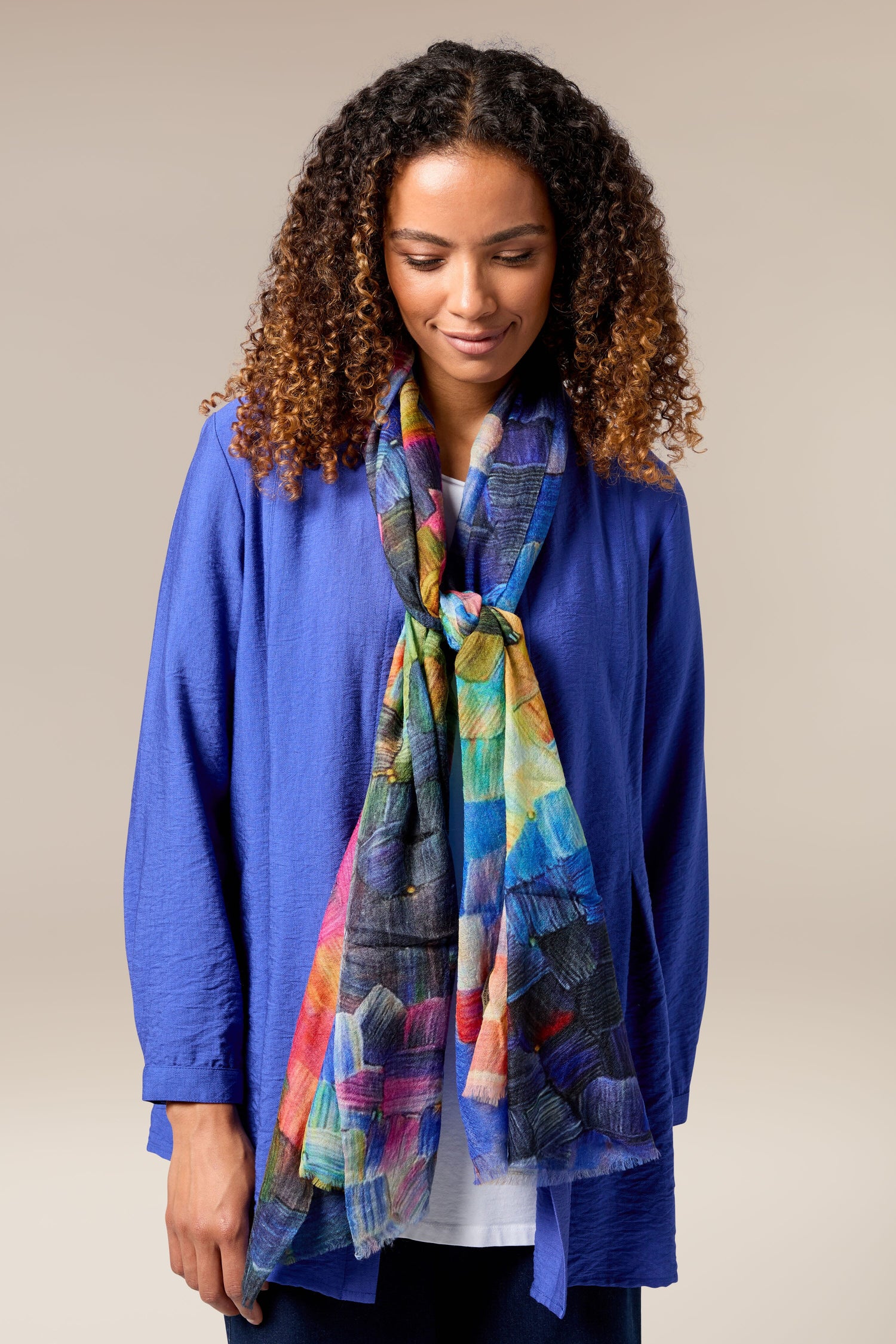 A woman wearing a luxurious blue jacket and Painterly Woollen Scarf, showcasing an exquisite accessory.