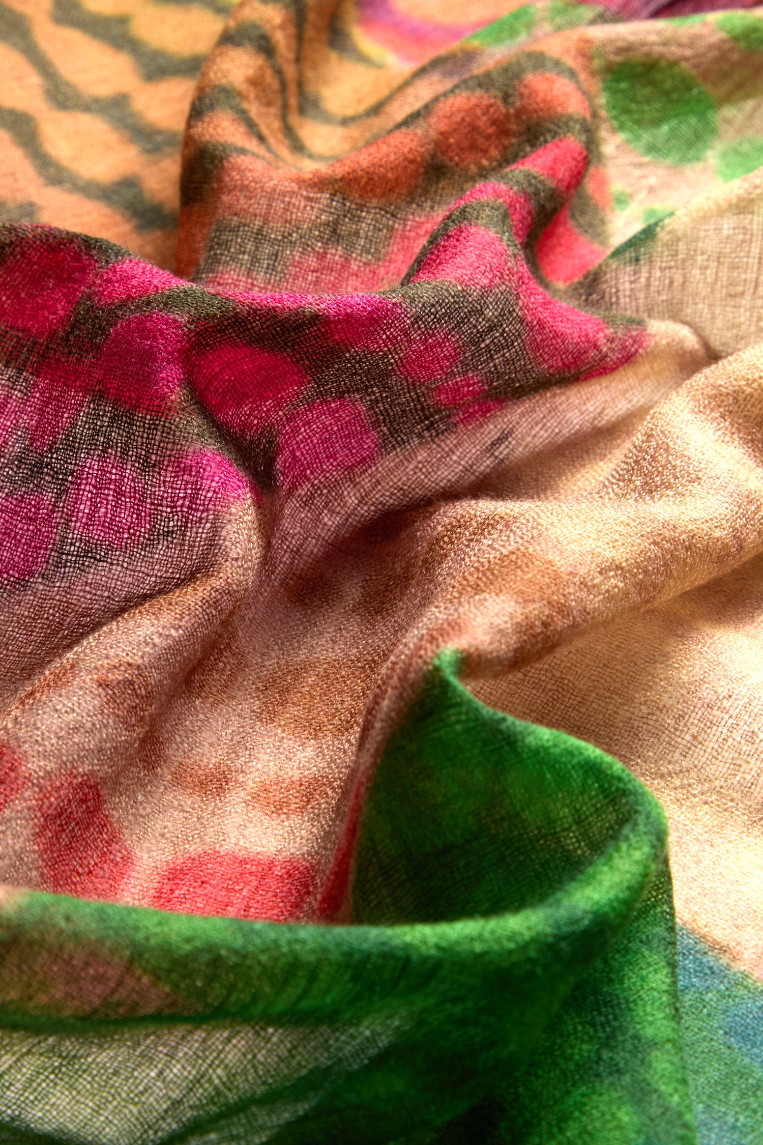 Close-up of the Circle Spot Merino Wool Scarf showcasing its colorful and textured design in shades of pink, green, and beige, with a mix of circle spot patterns and soft folds that provide lightweight warmth.