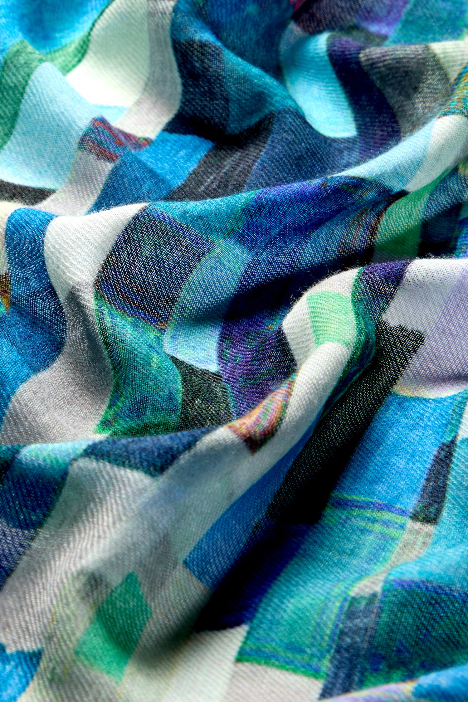 Close-up of the luxurious Ocean Squares Wool Scarf, showcasing its wavy, crumpled texture and chic square pattern in shades of blue, green, and white.