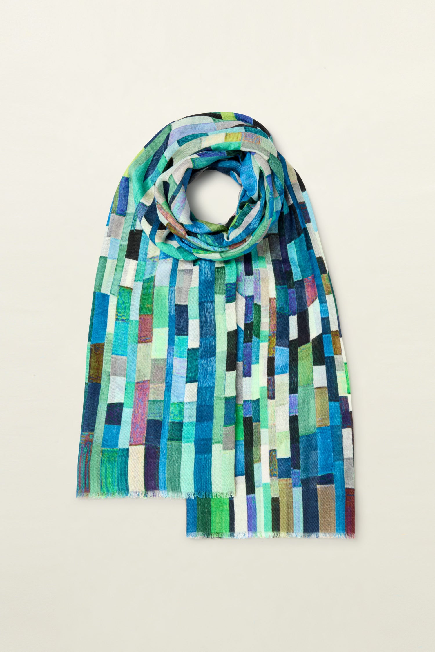 An Ocean Squares Wool Scarf featuring a chic square pattern of rectangular blocks in vibrant shades of blue, green, and other contrasting colors, artistically draped and displayed against a plain background.