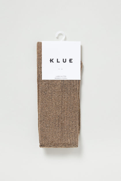 A pair of Bamboo Sparkle Caramel Socks featuring ribbed caramel fabric with a metallic sheen, packaged with a white "KLUE" label and hung on a white hook.