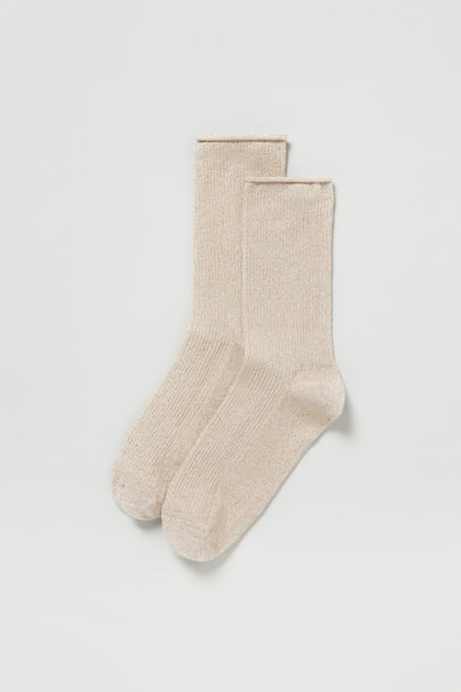 A pair of Bamboo Sparkle Sand Socks in beige with a ribbed texture is laid flat on a white background.