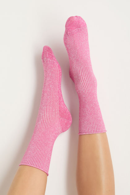 A person wearing Bamboo Sparkle Fuchsia Socks in sparkly pink ribbed fabric, legs extended upward against a white background.