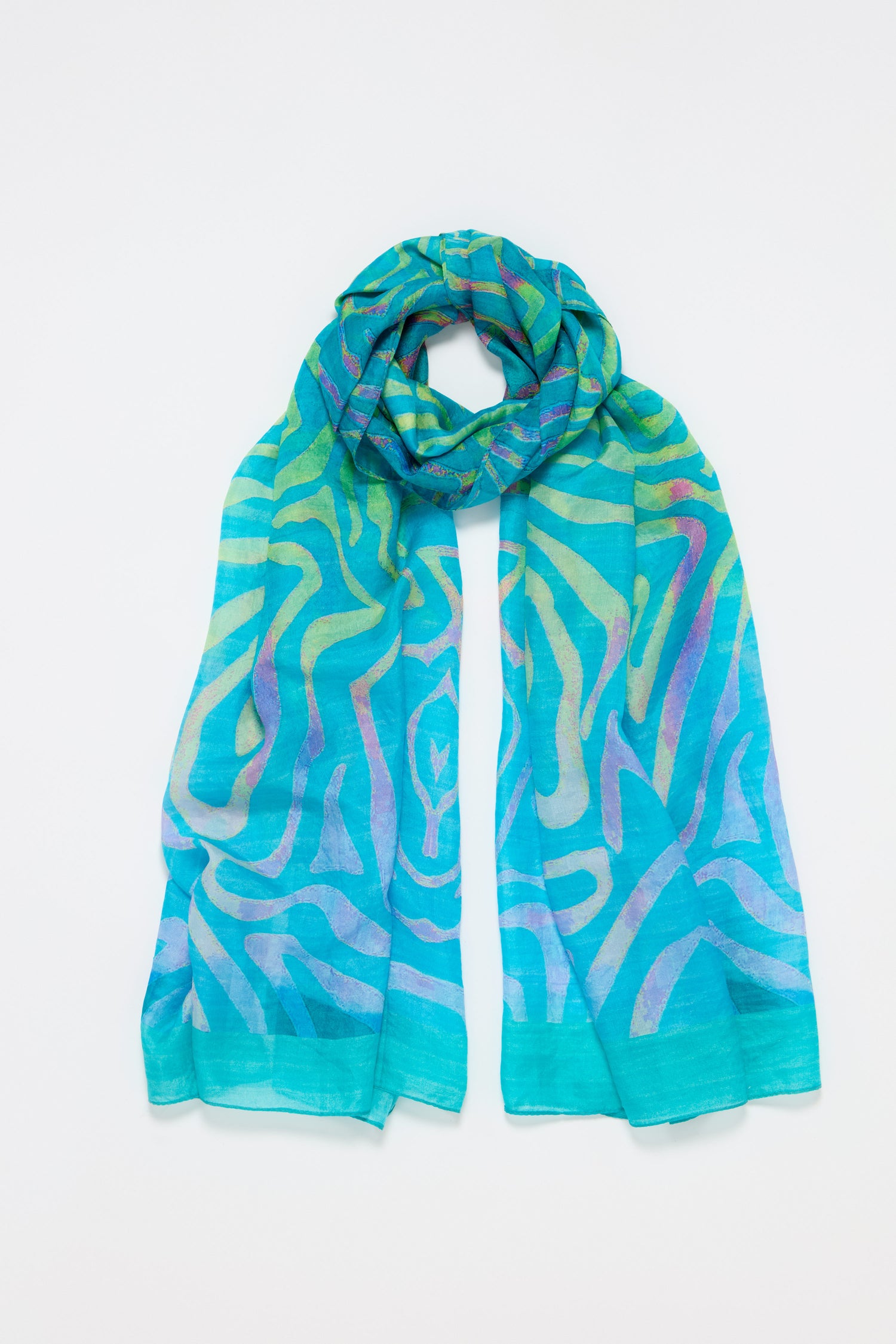 The Ripple Silk Scarf, shown flat on a white background, features abstract, wavy patterns in turquoise, green, yellow, and purple silk for an artistic touch.