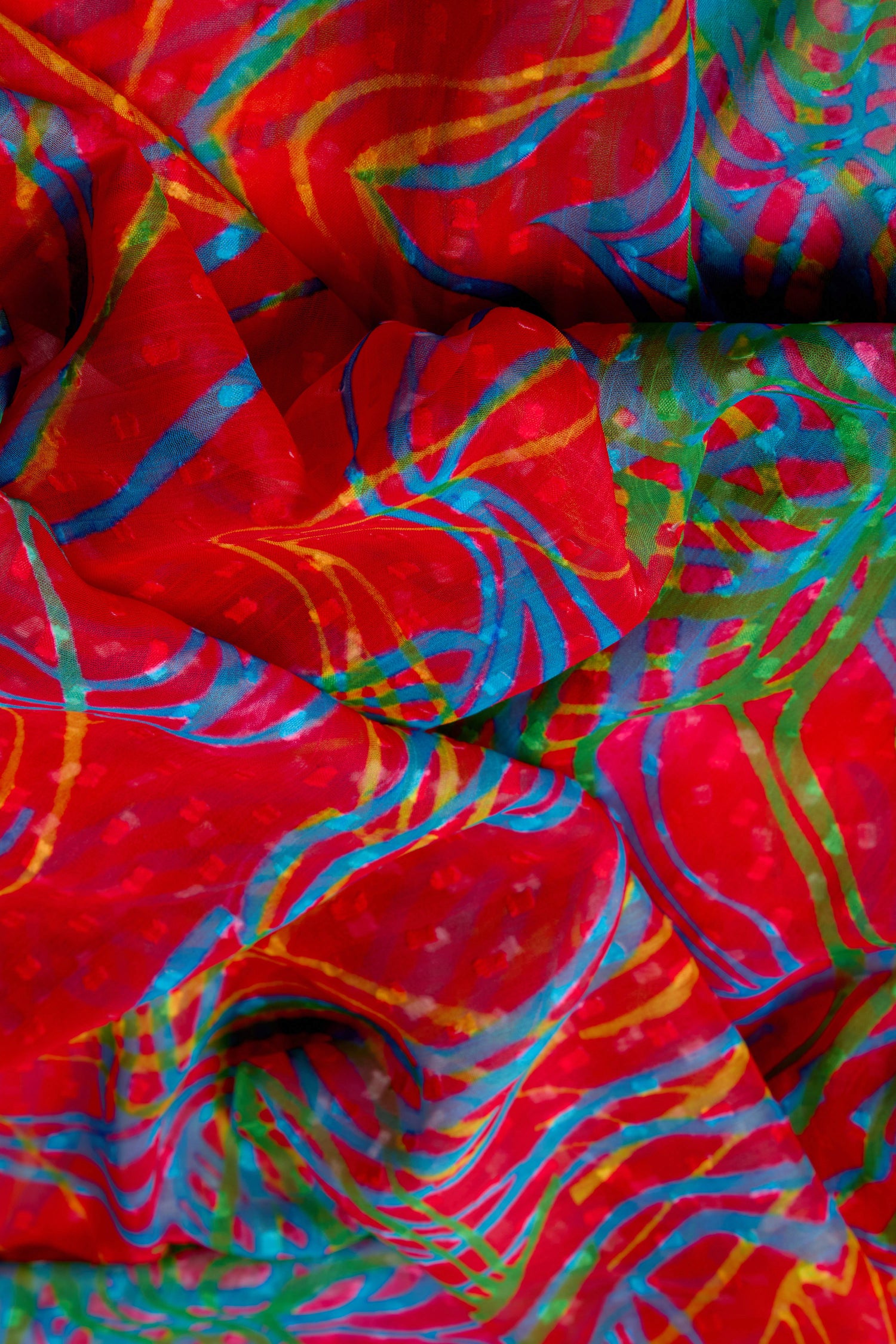 Discover the Twirl Print Dobby Scarf, crafted in lightweight fabric and featuring vibrant red, blue, green, and yellow abstract patterns with distinctive swirling lines and shapes.