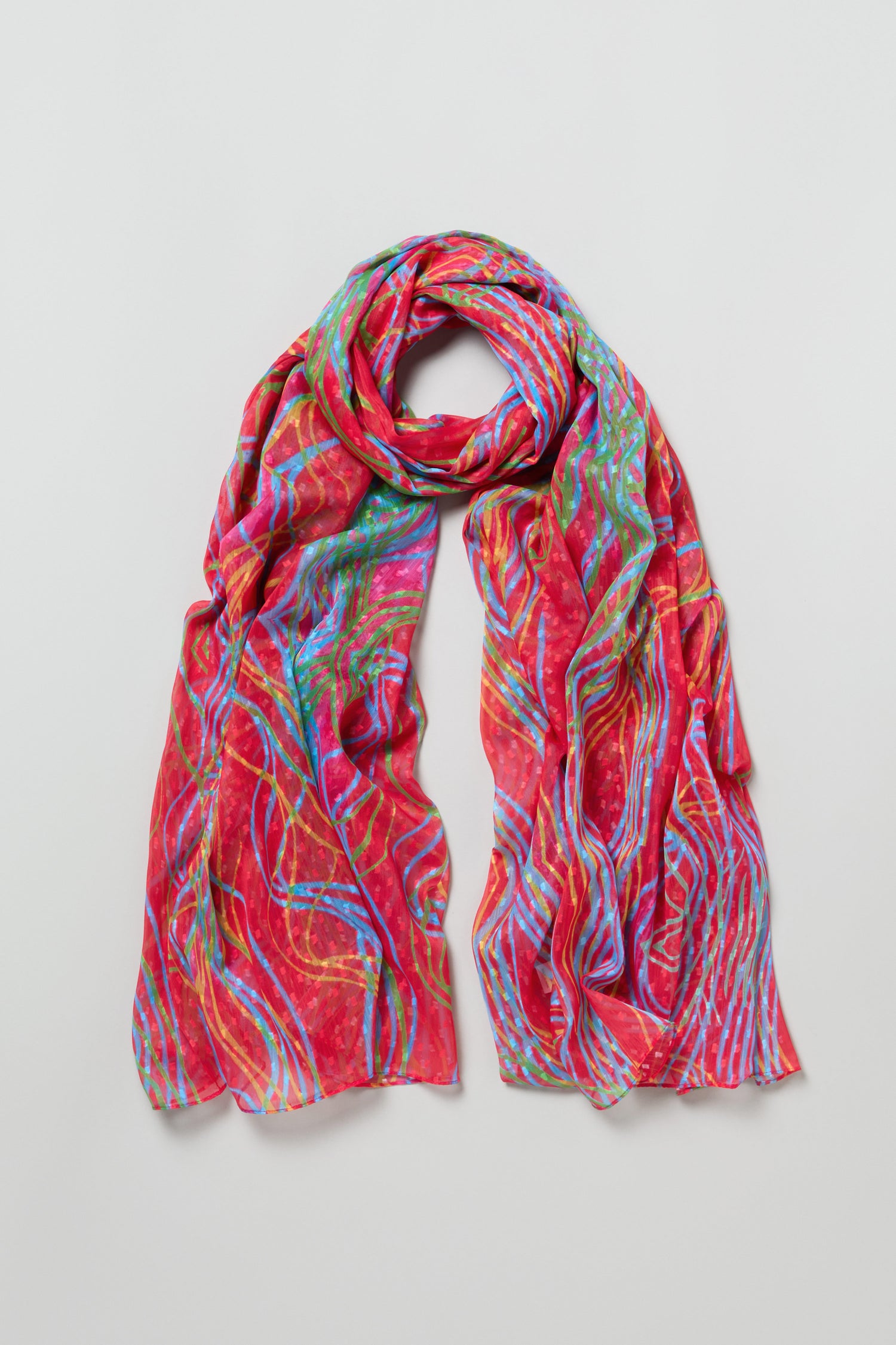 The Twirl Print Dobby Scarf is lightweight with a vibrant red base and abstract swirl prints in blue, green, and yellow lines, shown on a plain background.