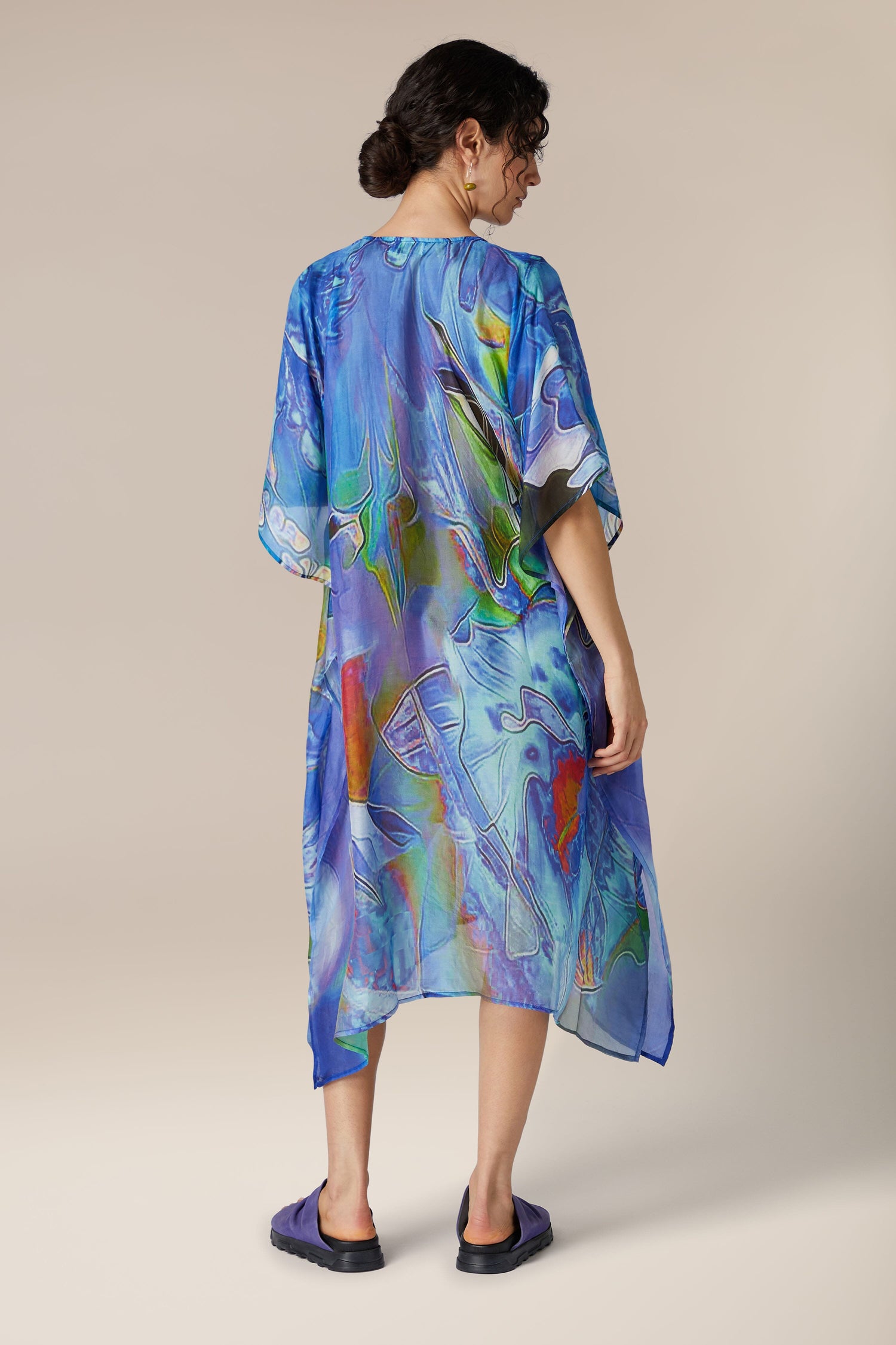 A woman seen from behind wearing a Tiffany Lamp Silk V Neck Kaftan and standing against a neutral background.