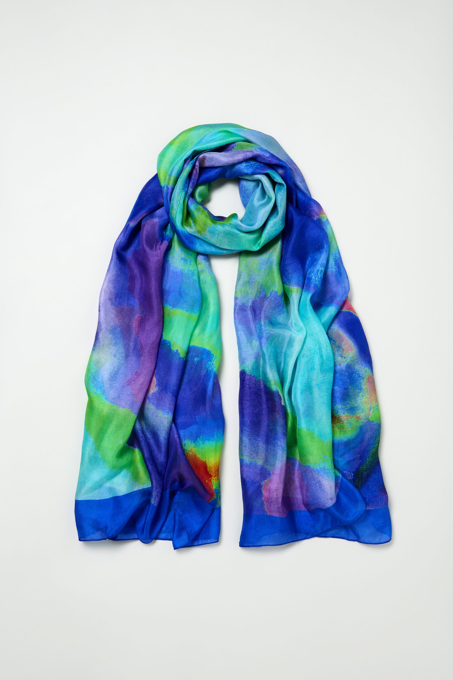The Aurora Veil Silk Scarf, a lightweight accessory with an abstract blue, green, and purple print, is laid flat on a plain background.
