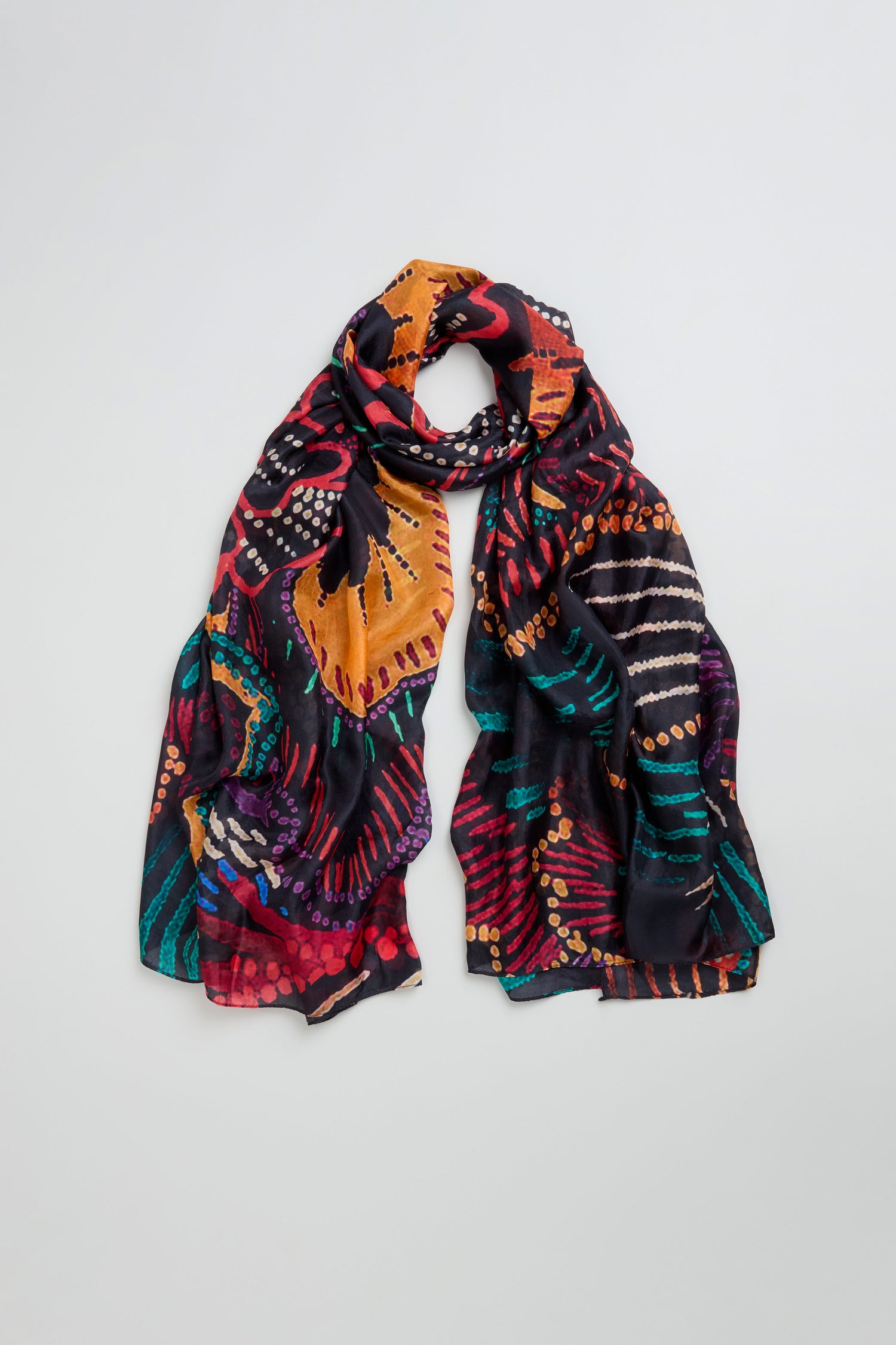 The Painted Firework Silk Scarf is a lightweight, colorful silk accessory with abstract orange, red, purple, green, and black patterns shown on a light background.