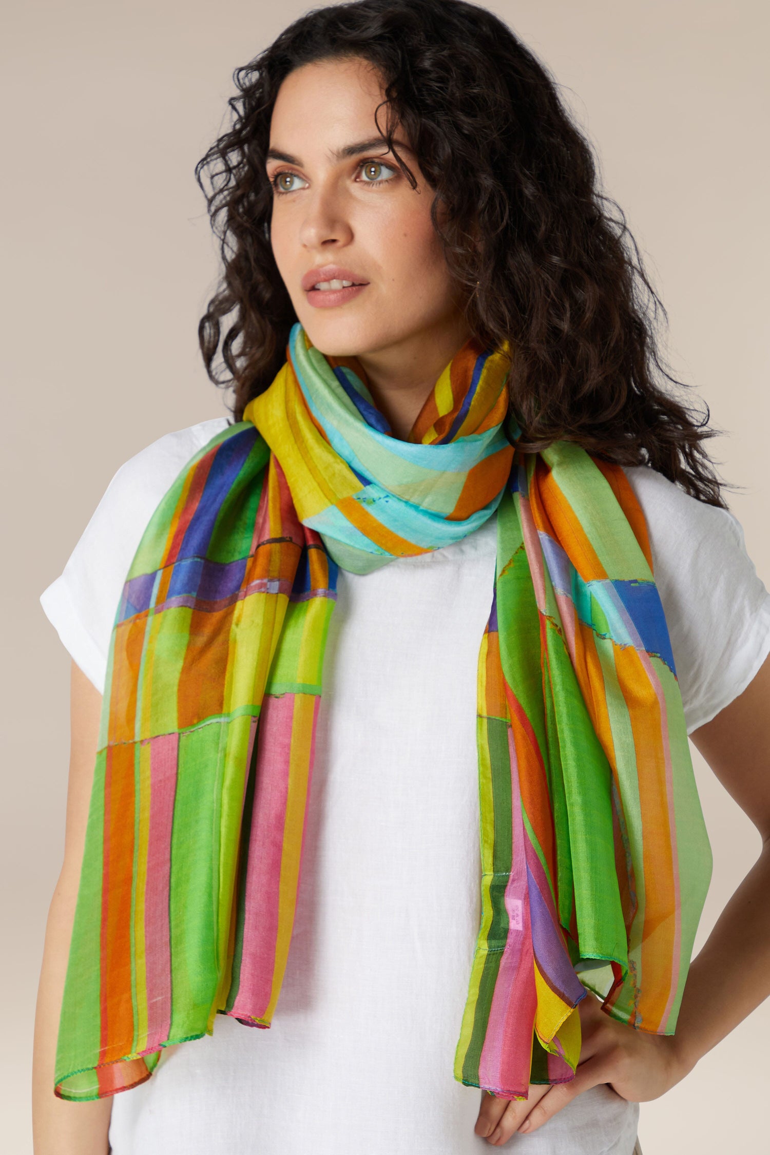 Woman wearing a white top and a vibrant Geometric Silk Scarf.