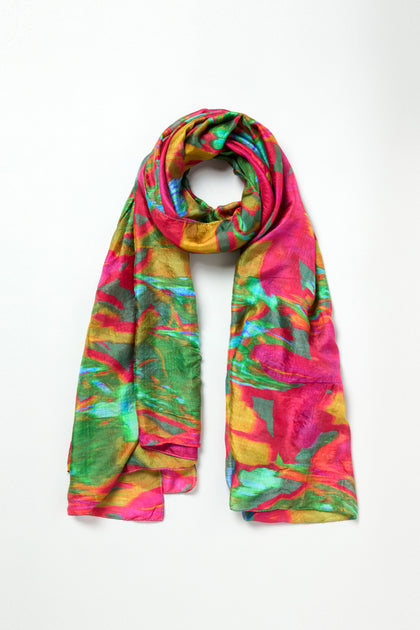 Elevate your look with the Blurred Botanicals Scarf, a lightweight accessory showcasing a vivid abstract pattern in pink, green, yellow, and blue on a crisp white background.