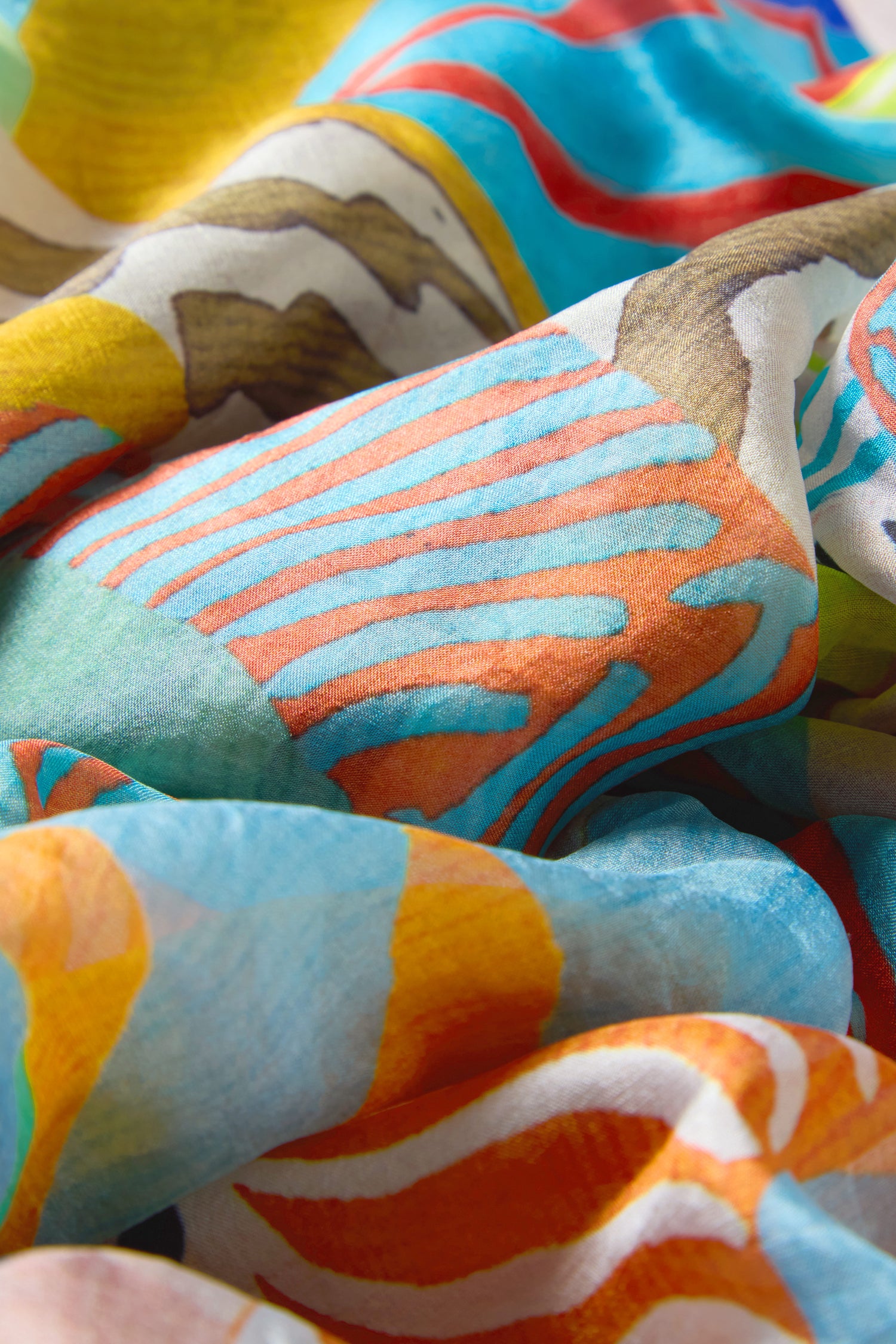 Close-up of the Tropical Orchid Fantasy Silk Scarf, featuring colorful abstract patterns and tropical prints in blue, orange, yellow, brown, and white tones.
