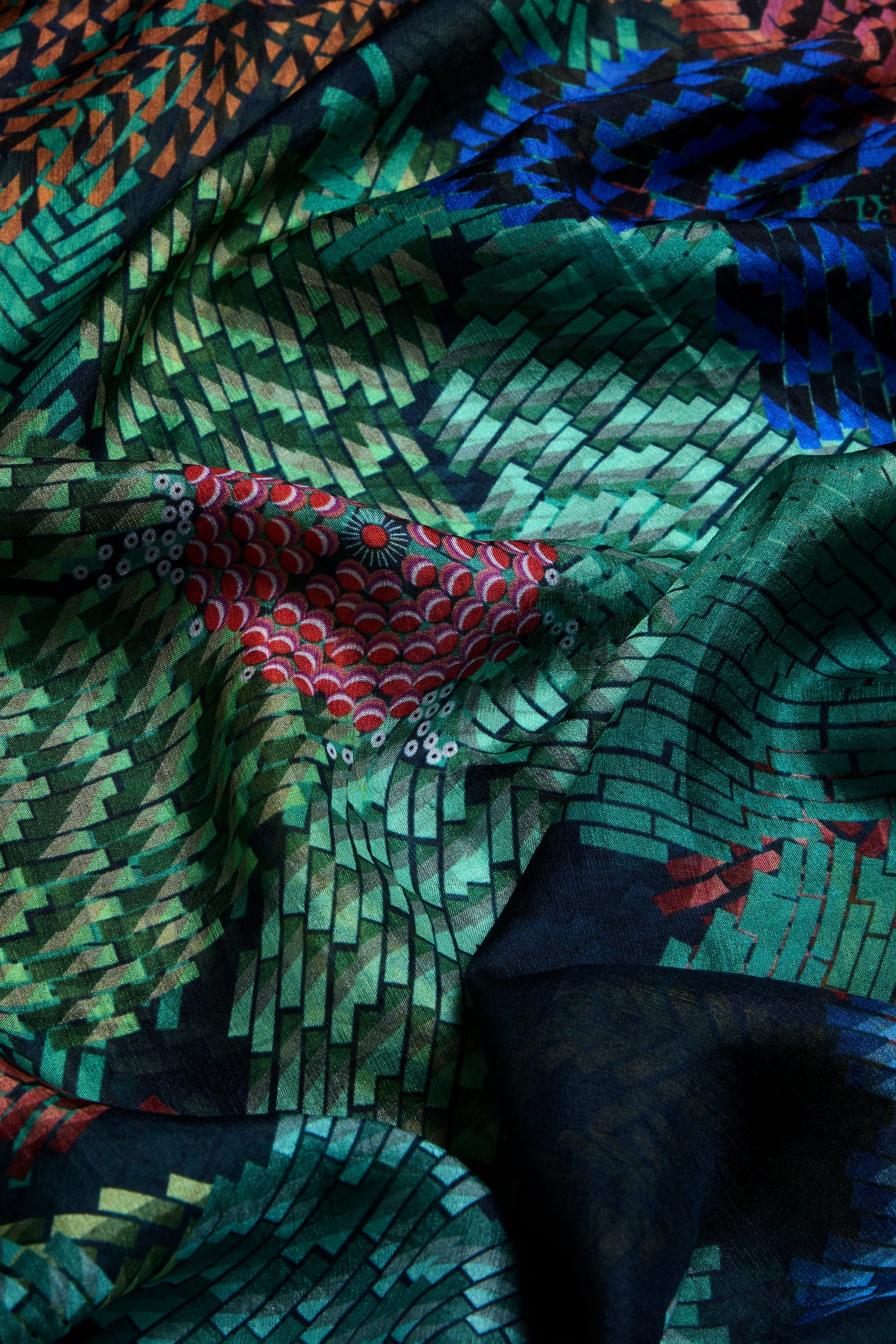 A close-up of the Pixelated Petals Silk Scarf, showcasing its geometric, mosaic-inspired floral print in vibrant shades of green, red, blue, and black.