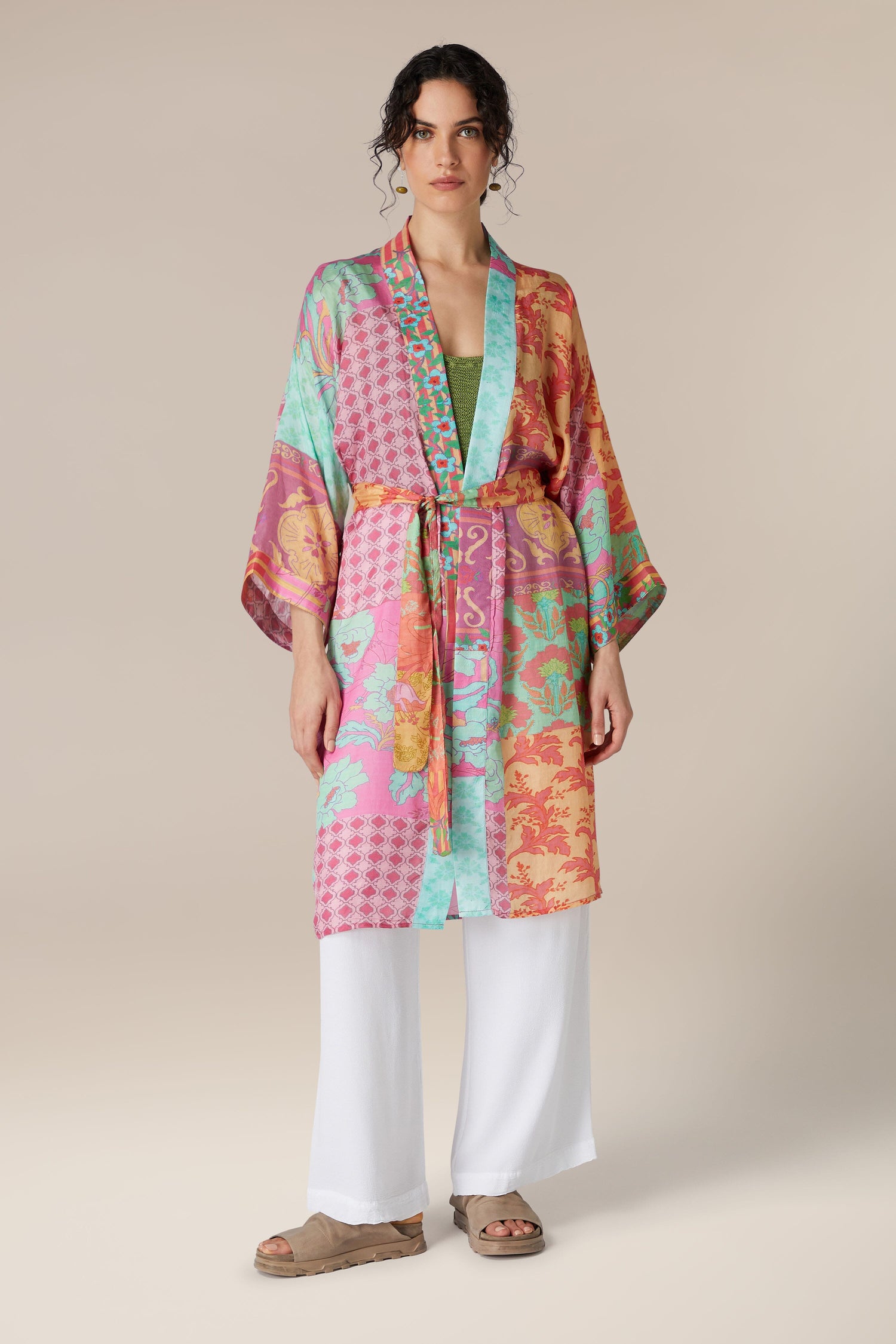 Woman modeling a colorful Geometric Floral Silk Kimono over white trousers with neutral sandals.