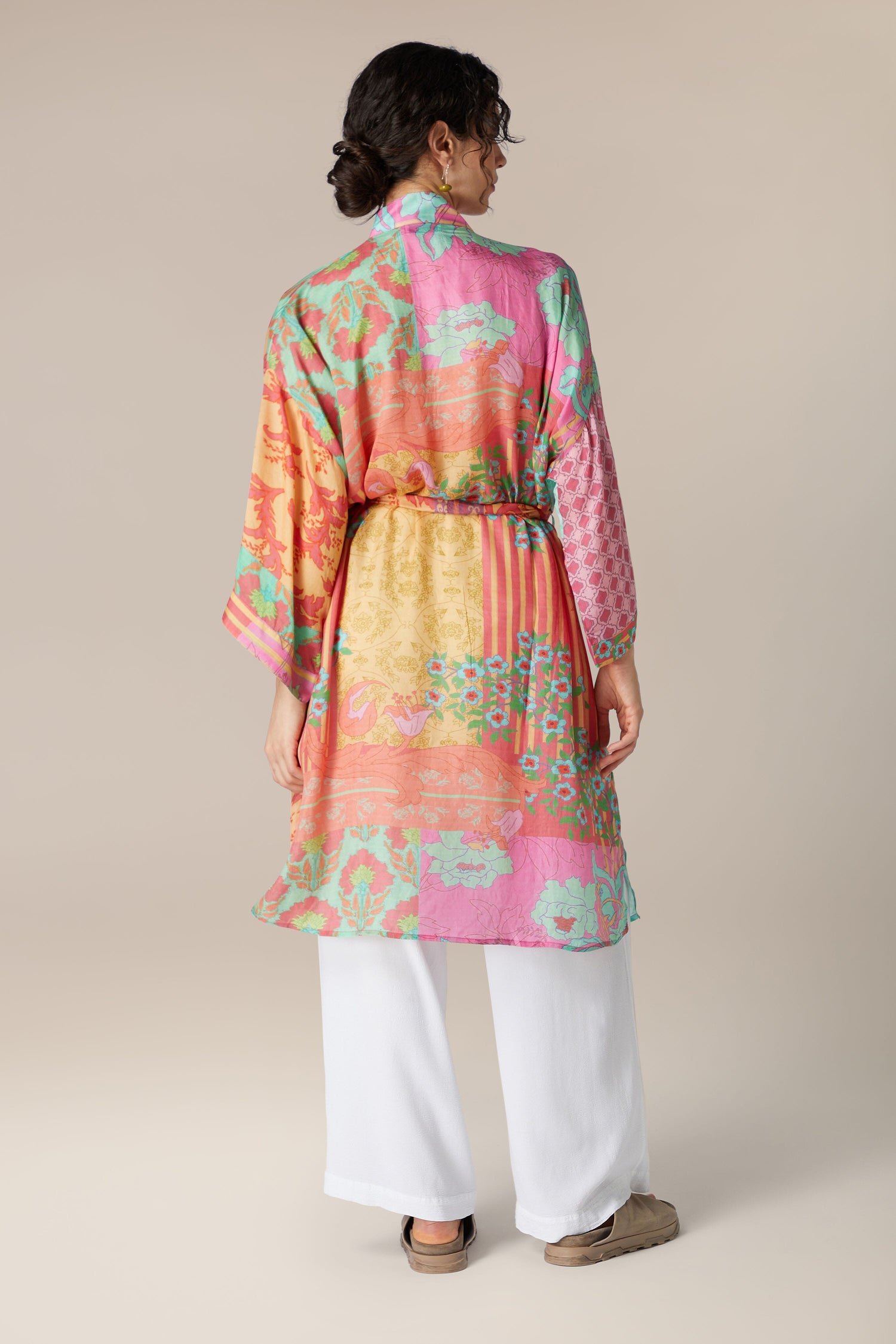 A person viewed from behind, wearing a luxury Geometric Floral Silk Kimono over white trousers, standing against a neutral background.