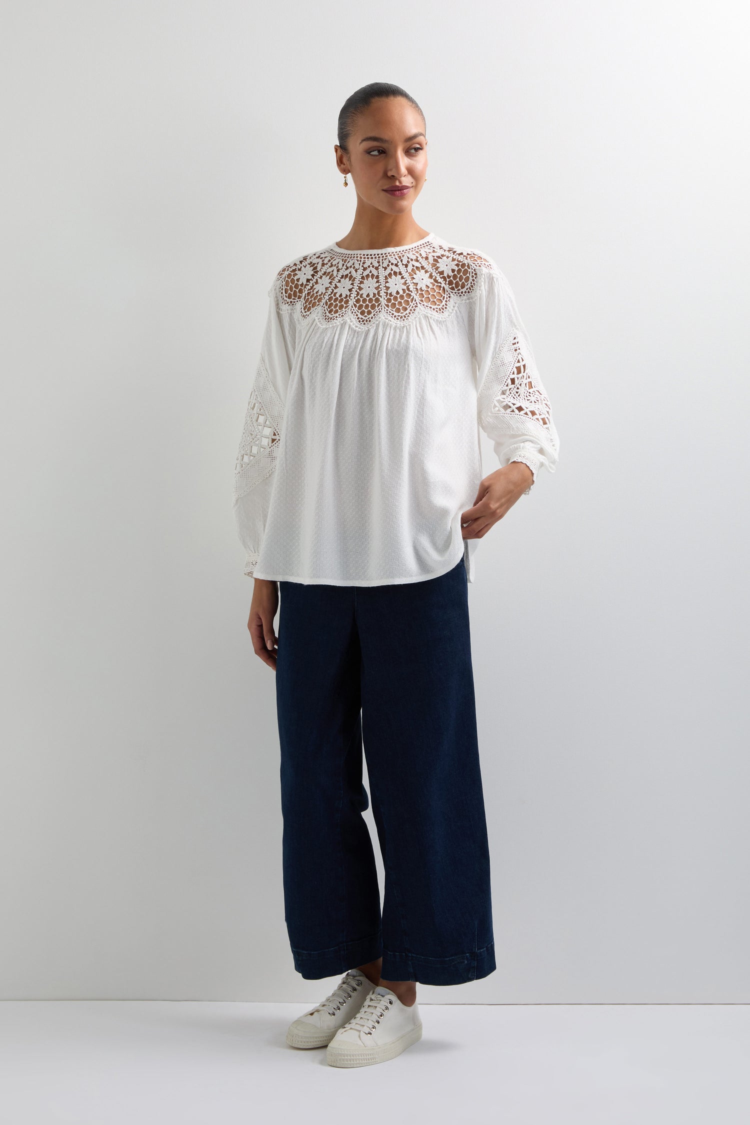 A person wearing the Floral Lace Trim Top, paired with dark wide-leg pants (style code KNT6038-FLA), and white sneakers stands against a plain background.