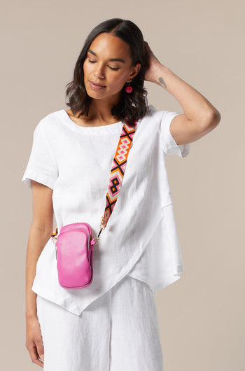 A woman wearing white pants and a pink Mini Crossbody Bag showcasing style-led designs.