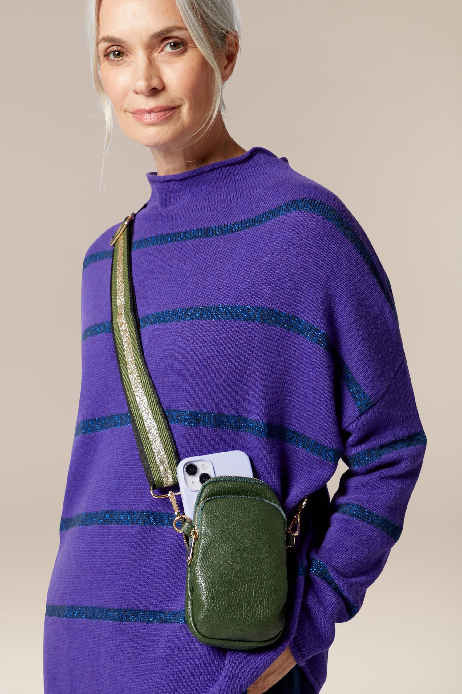 A woman, stylishly adorned in a purple sweater, carries her essentials in a Mini Crossbody Bag.