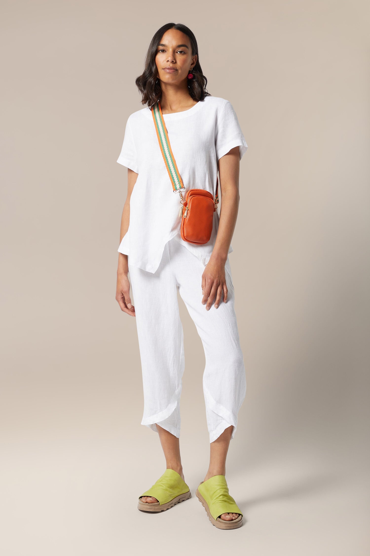 A woman wearing white pants and holding a Mini Crossbody Bag, showcasing Kris-Ana's style-led designs.