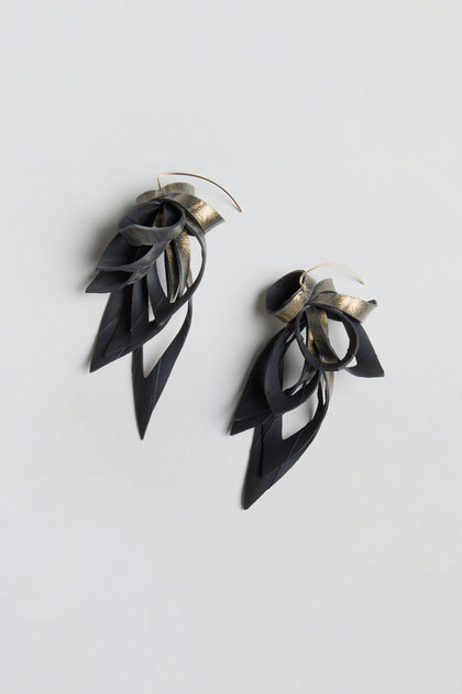 Gold Flipped Leaves Earrings, crafted from reclaimed bicycle inner tube, feature layered black and gold metallic loops with pointed leaf drop shapes, and are showcased on a light gray background.