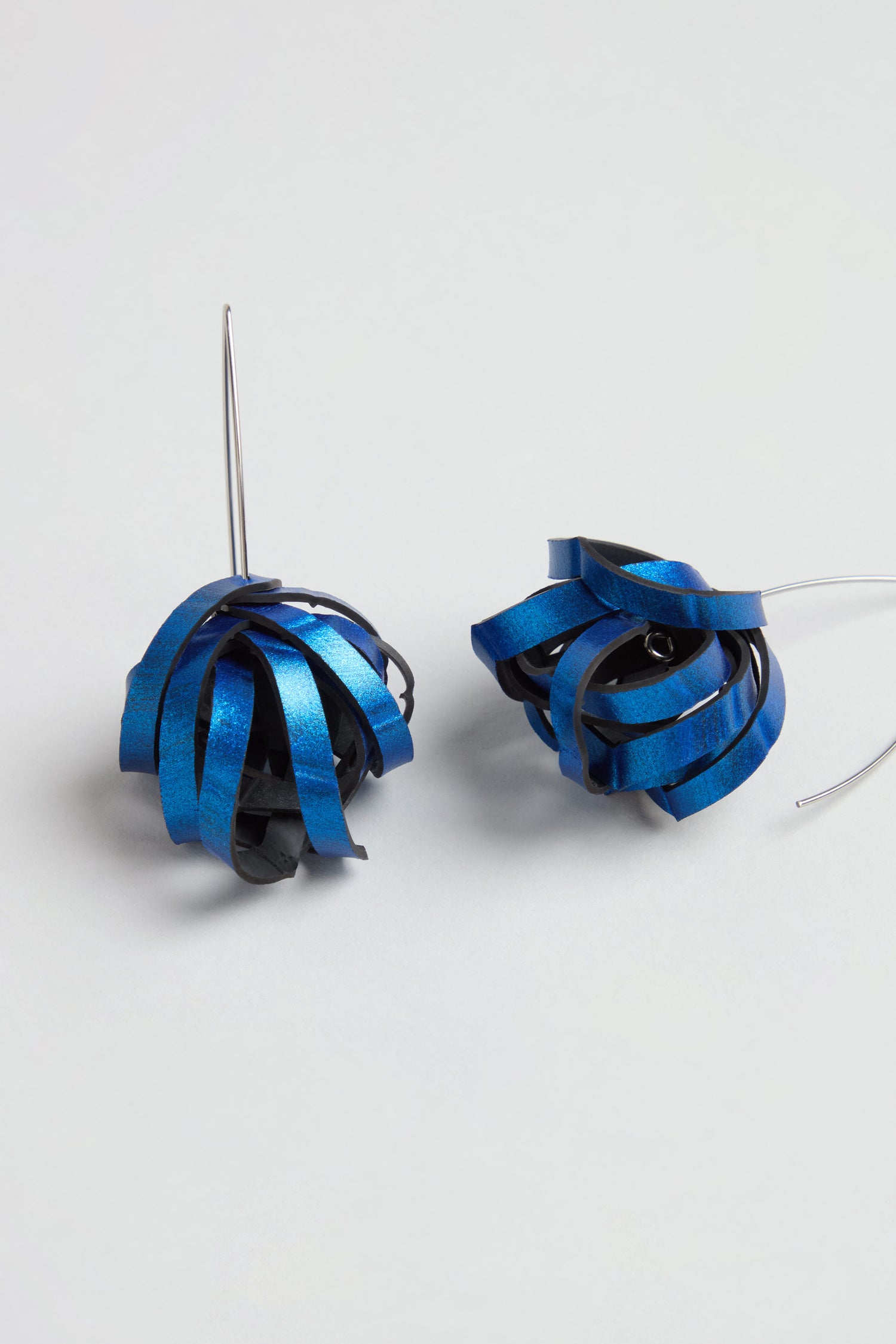 Metallic Blue Pom Pom Earrings featuring upcycled blue and black curled ribbon-like elements and thin silver hooks, displayed on a plain surface.