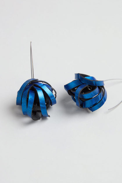 Metallic Blue Pom Pom Earrings featuring upcycled blue and black curled ribbon-like elements and thin silver hooks, displayed on a plain surface.