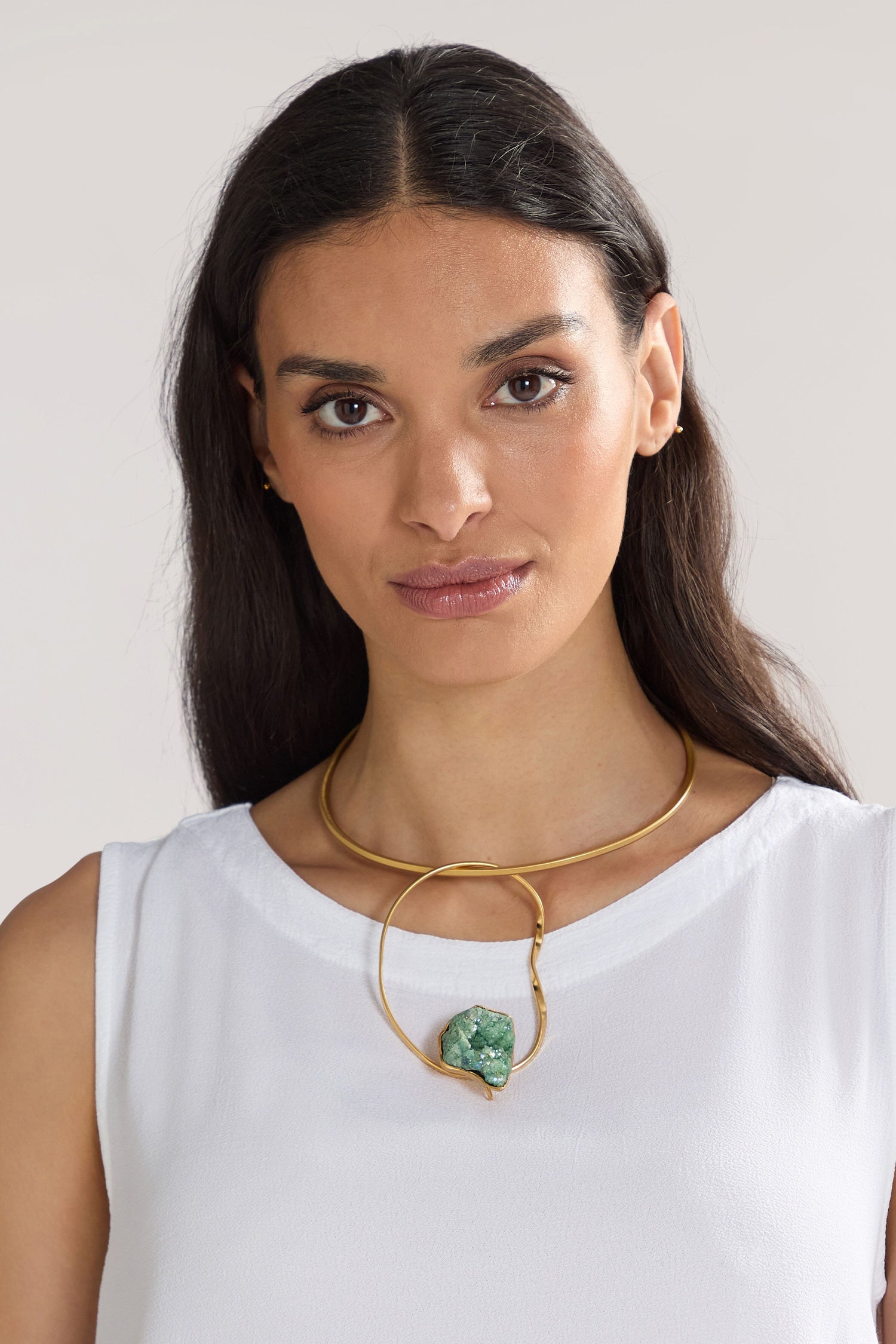 A woman with long dark hair is wearing a white top and a 24k gold plated brass Handmade Agate Hoop Necklace featuring a semi-precious agate stone.