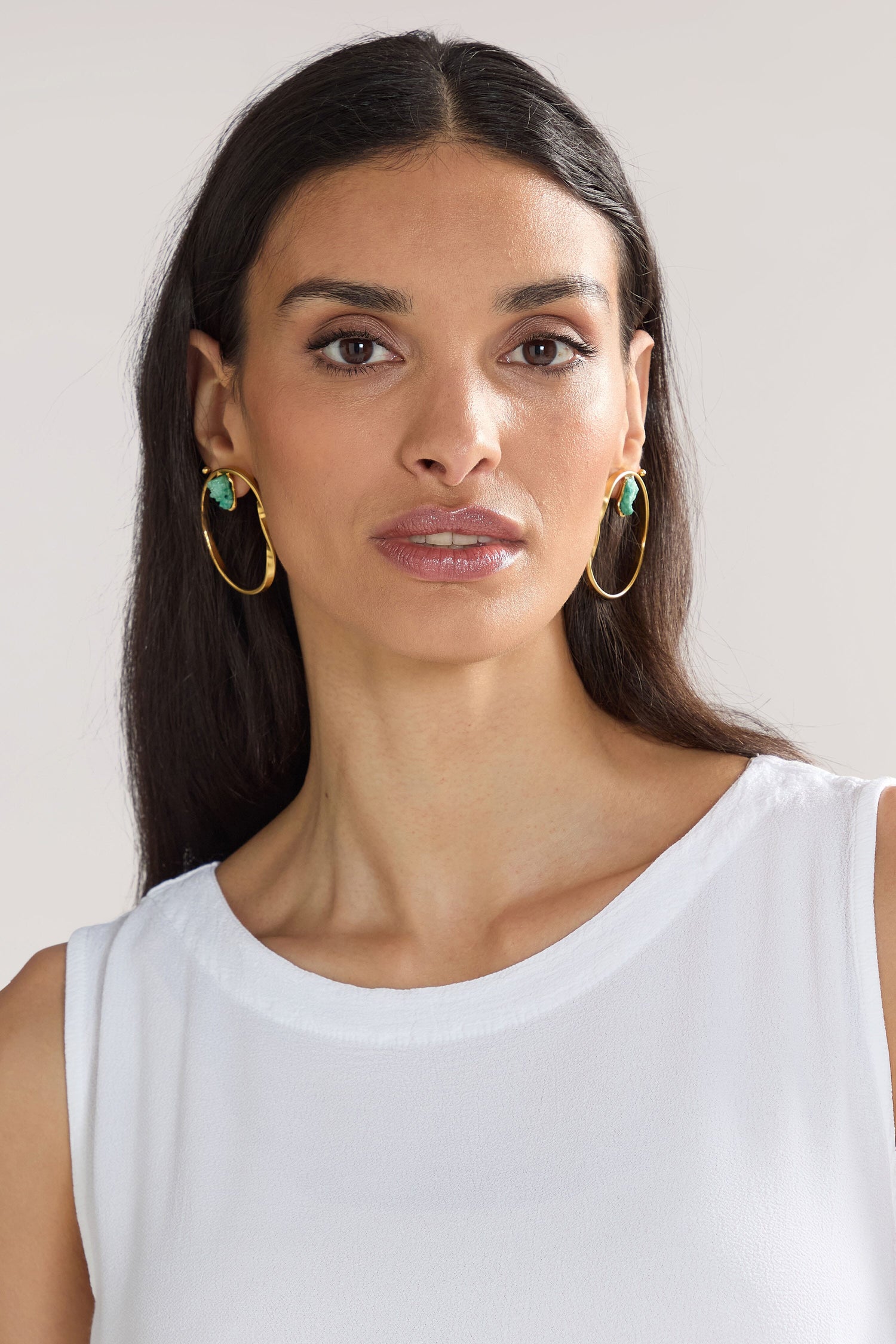 A woman with long dark hair and Handmade Agate Hoop Earrings—crafted from semi-precious agate stone—is wearing a white sleeveless top, facing the camera against a plain background.