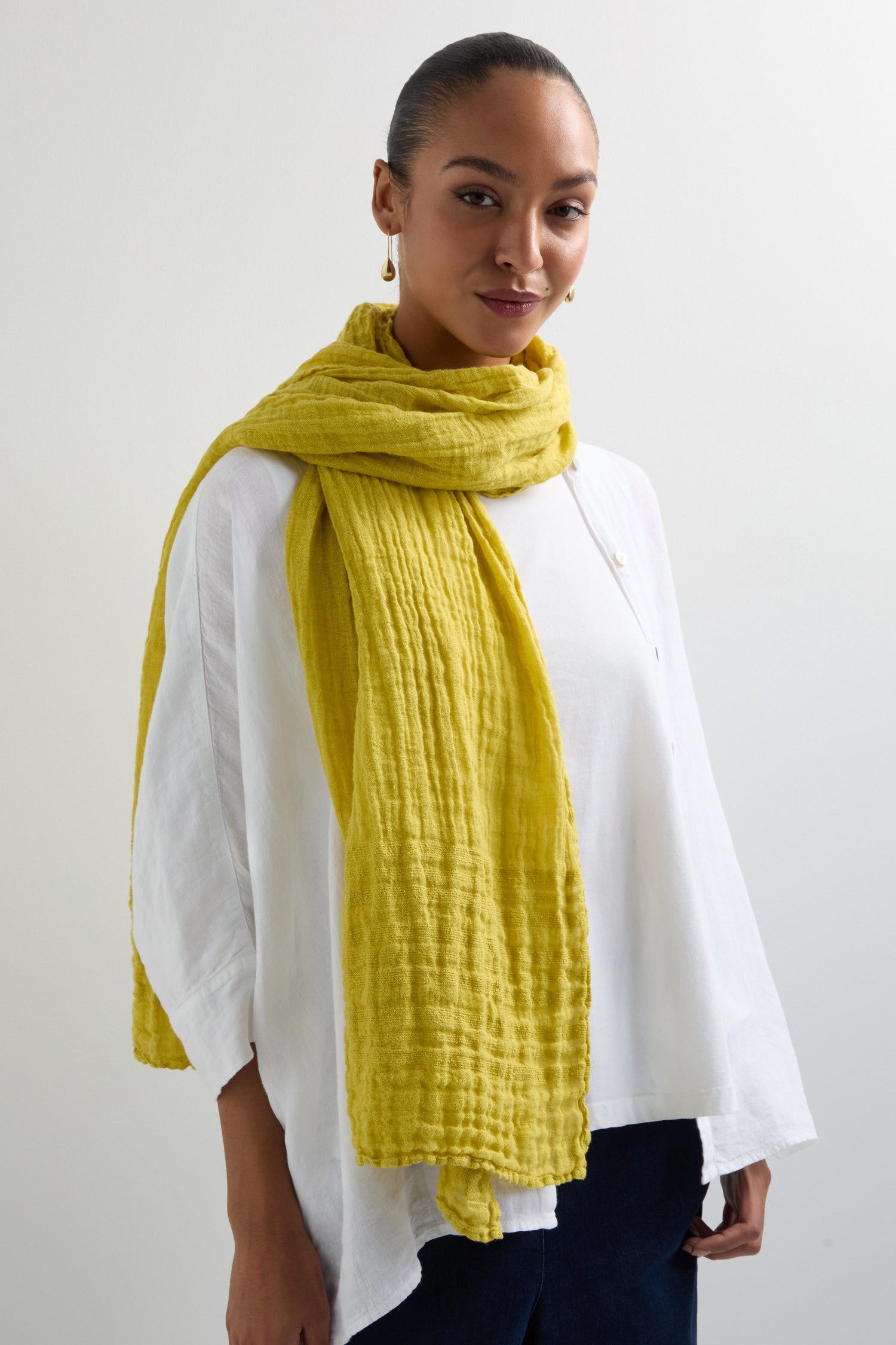 A person in a white shirt and a Crinkle Linen Scarf with a textured design stands against a plain background.