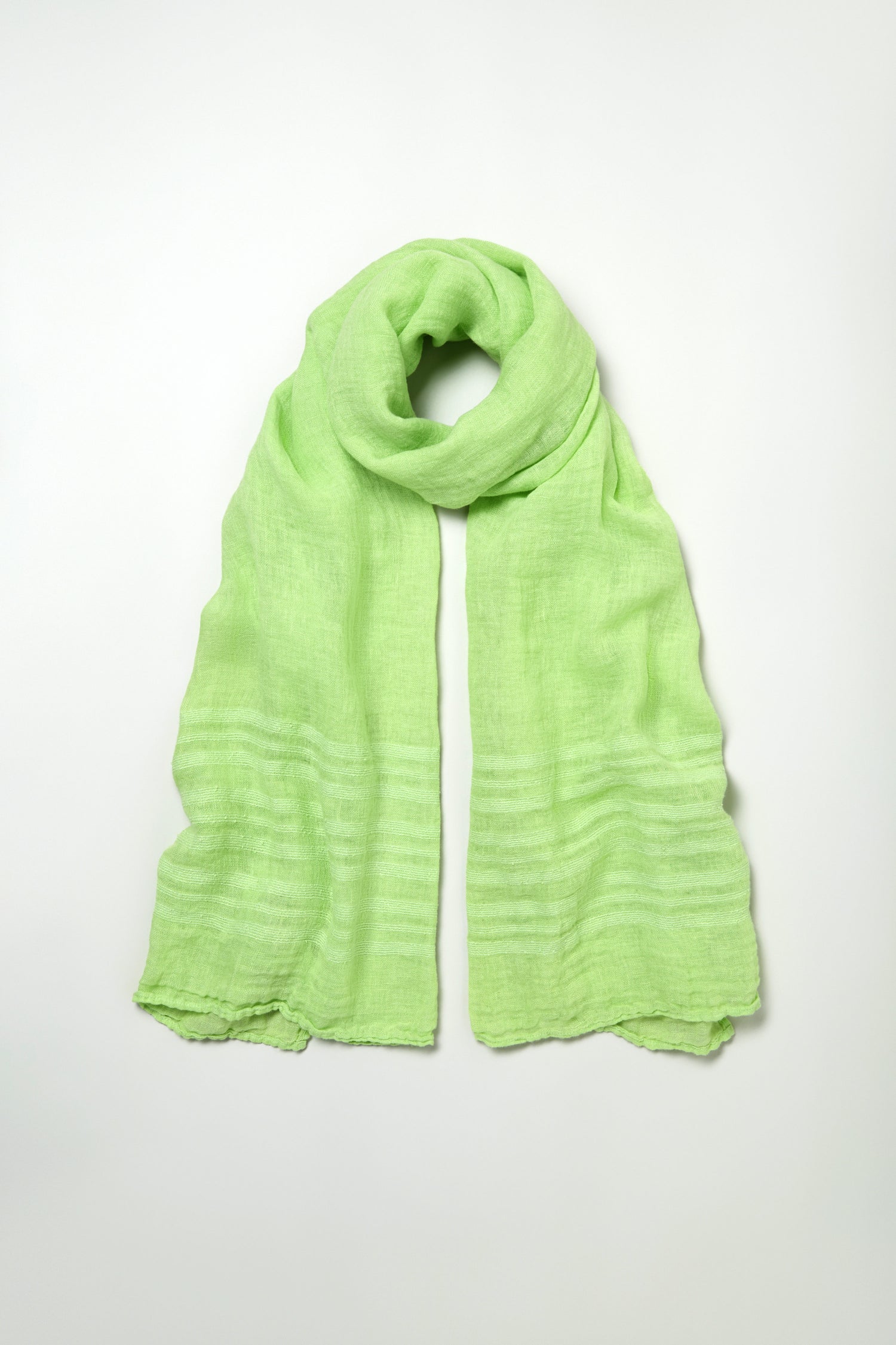 The Crinkle Linen Scarf in light green, crafted from lightweight textured fabric, is displayed in a loose loop with both ends visible against a plain white background.