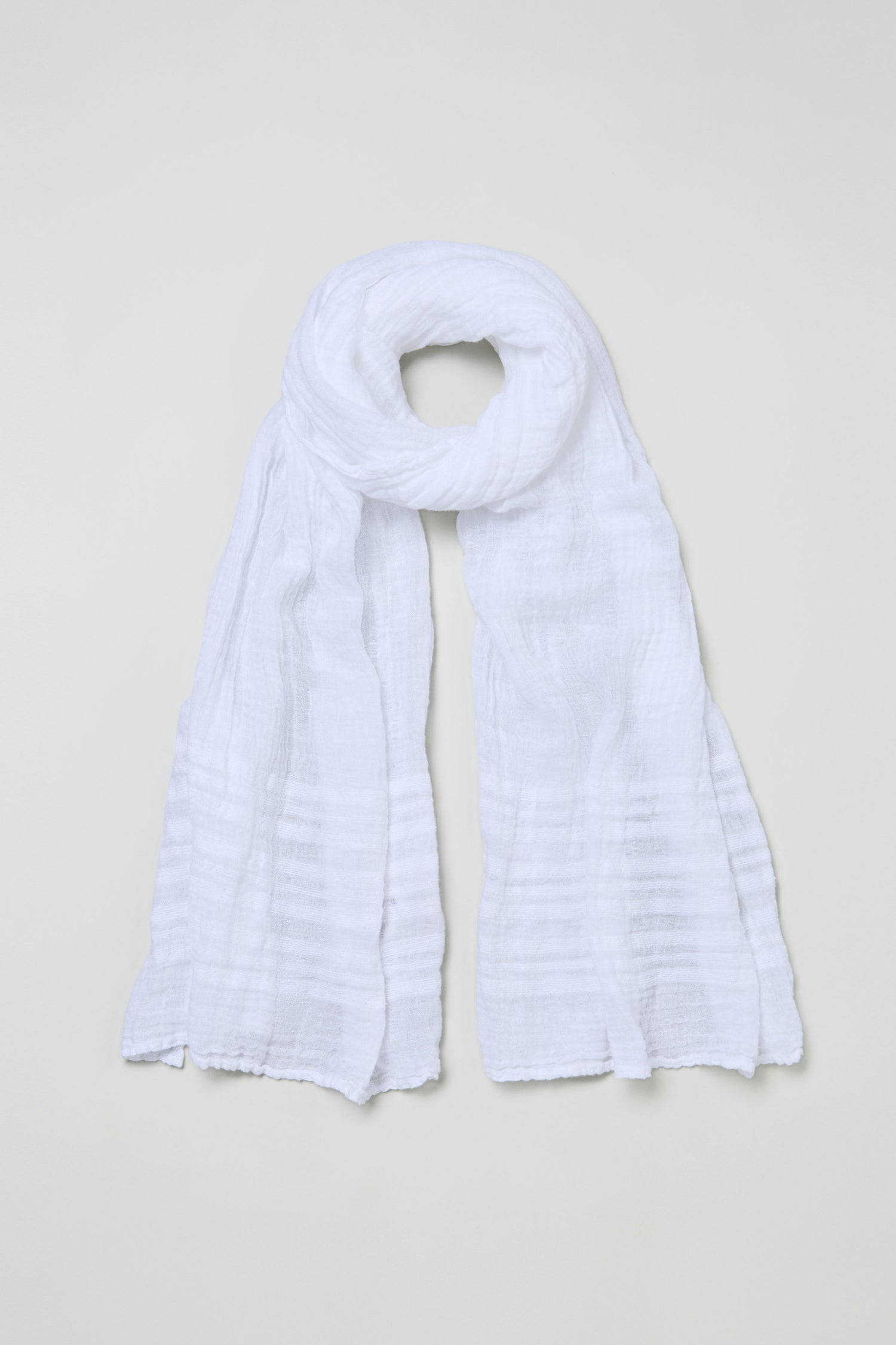 The Crinkle Linen Scarf is displayed flat on a light background, highlighting its white color and lightweight, textured fabric.
