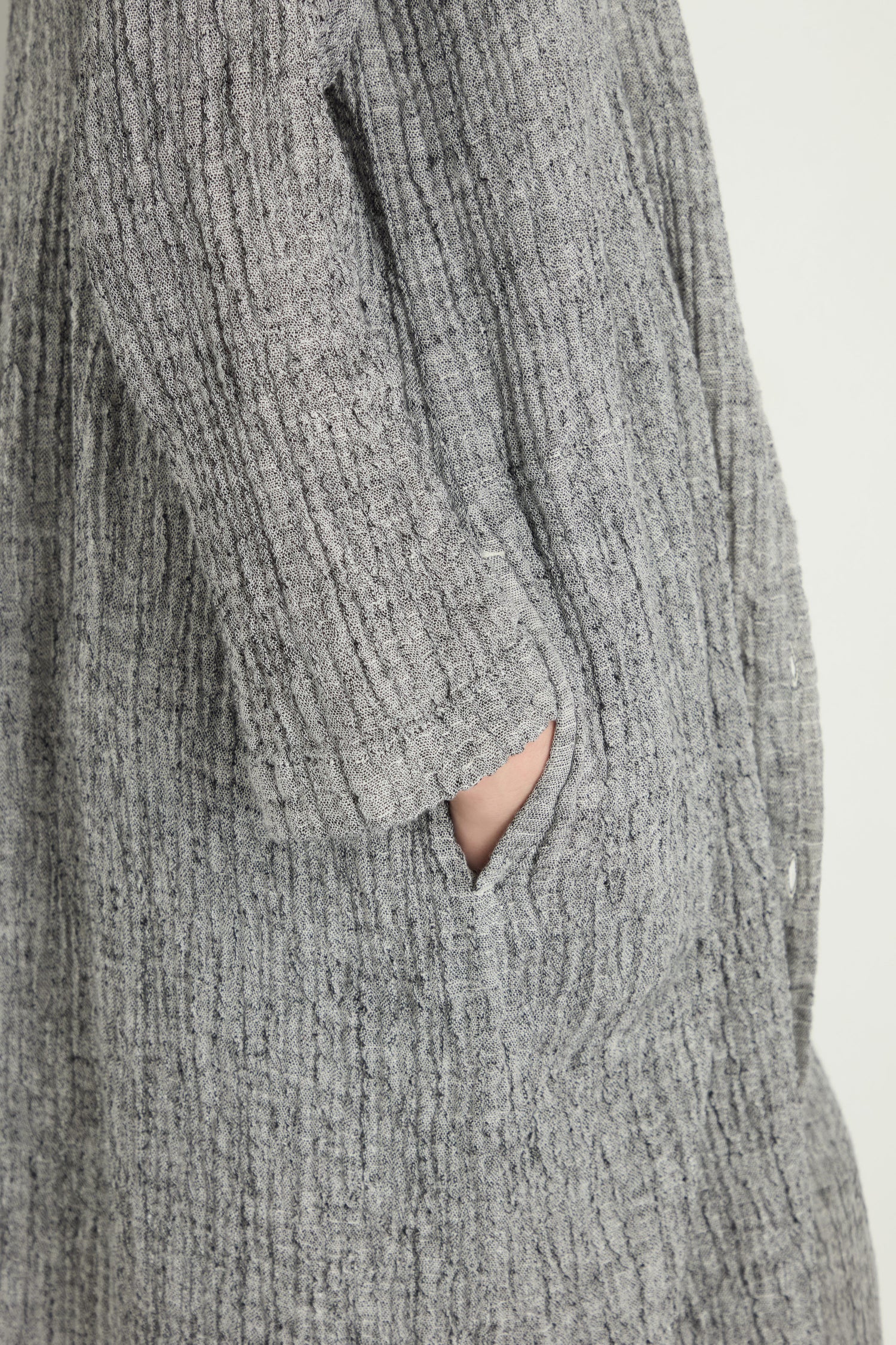 A person wearing the Crinkle Double Face Linen Shirt Dress in textured gray has their hand partially tucked into a side pocket.