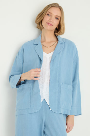 A woman models the Twisted Linen Boxy Jacket in light blue with matching pants over a white textured top, standing against a plain light background.