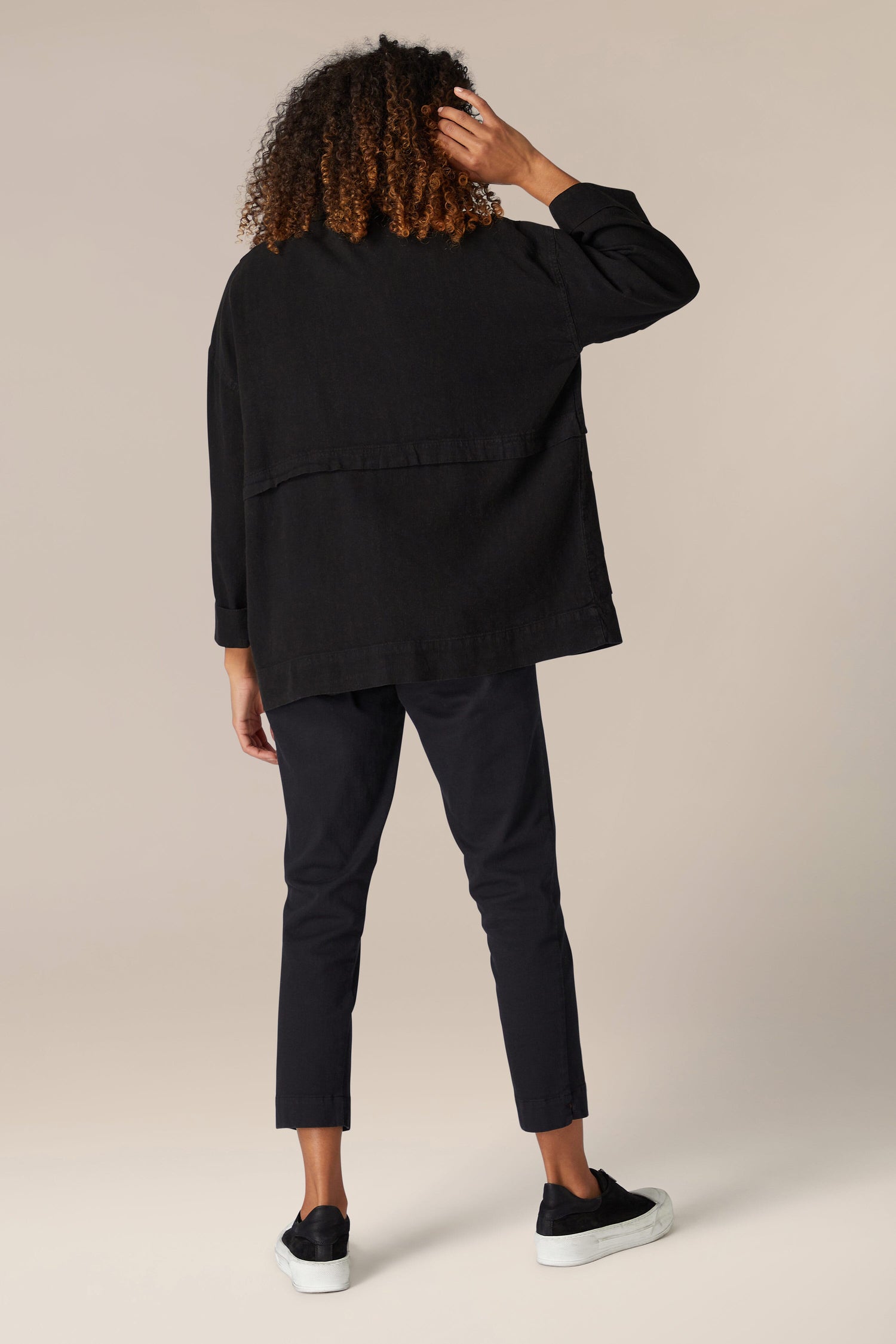 The woman is wearing a Twisted Linen Boxy Jacket and pants, creating a back view with a boxy silhouette.