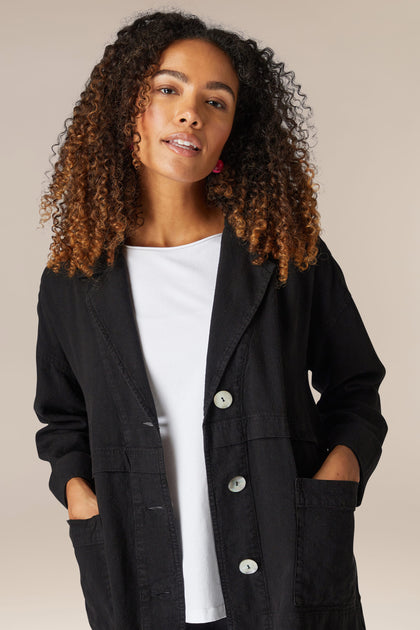 A woman wearing a Twisted Linen Boxy Jacket and white t-shirt.