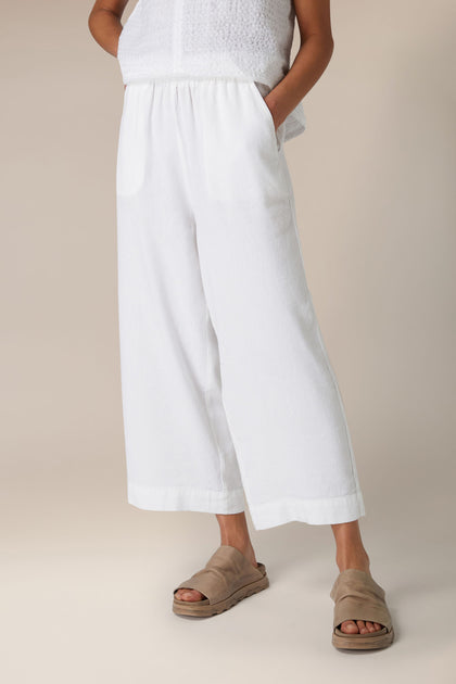 Sentence with Product Name: A person standing in a neutral stance wearing the Texture Linen Wide Trouser and beige slide sandals against a plain background.