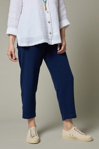 A woman wearing a white shirt and blue Twisted Linen Slim Trousers.