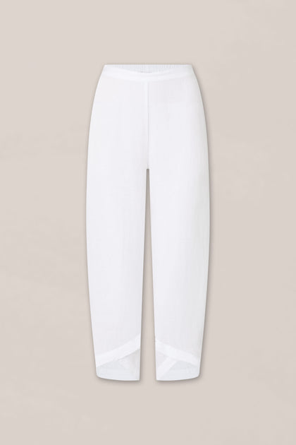 The Linen Bubble Trouser_AW23 features white linen fabric, a high waist, straight legs, diagonal seam detail at the hem, and an elasticated waistband, shown against a plain beige background.