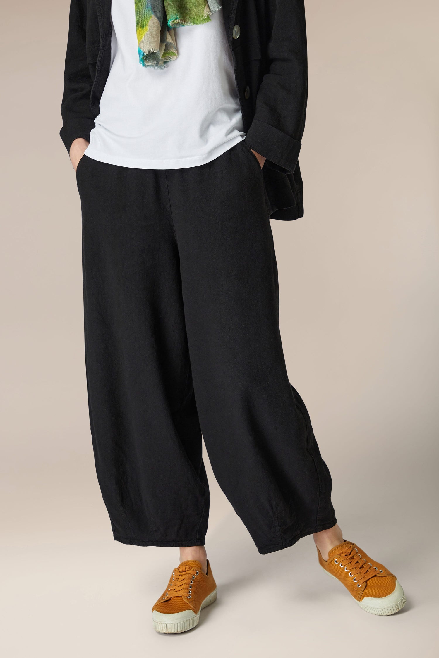 A woman wearing black Twisted Linen Bubble Trousers with an elasticated waistband and a green t-shirt.