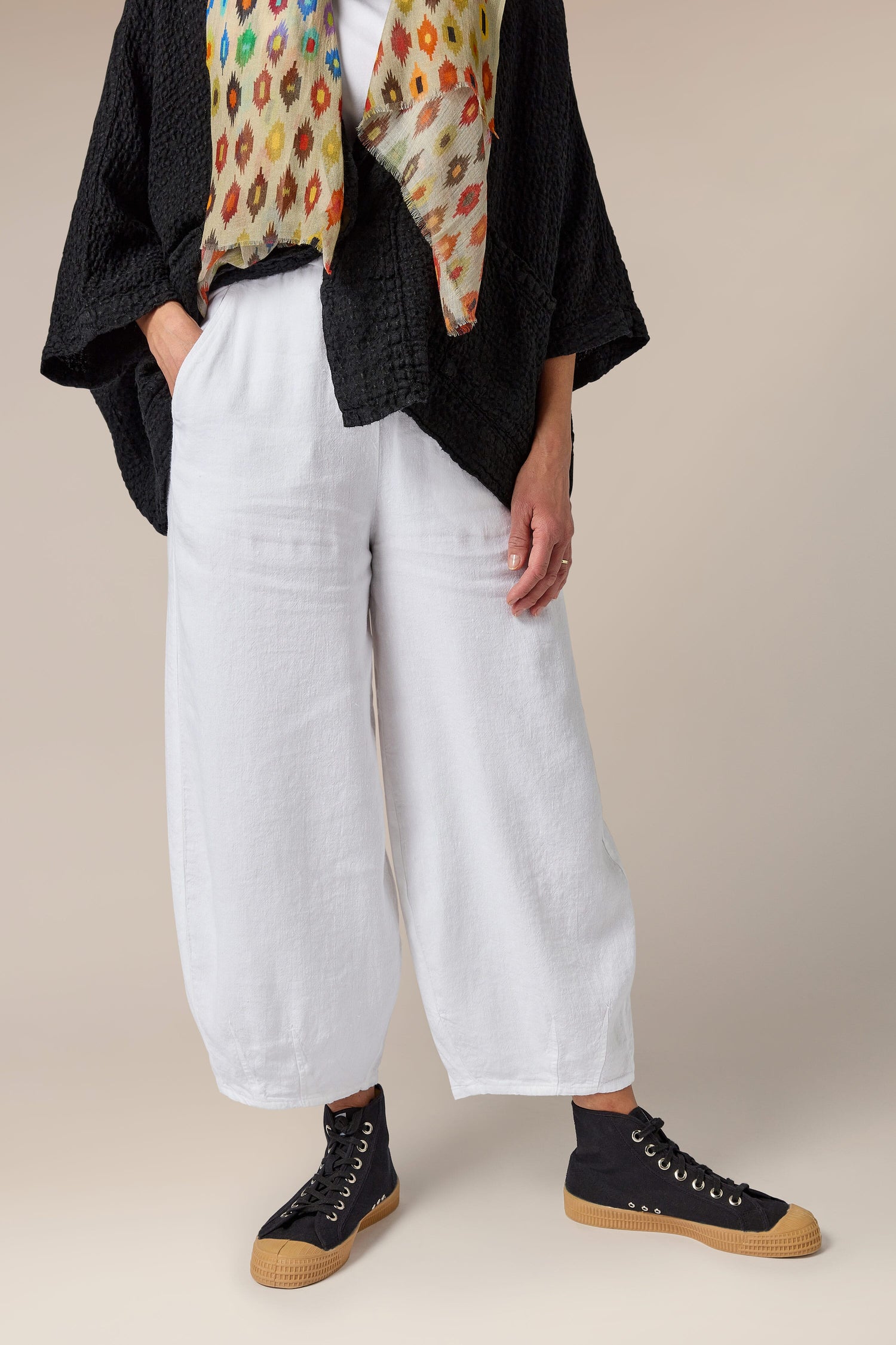 A woman wearing Twisted Linen Bubble Trouser pants with side pockets and a colorful scarf.