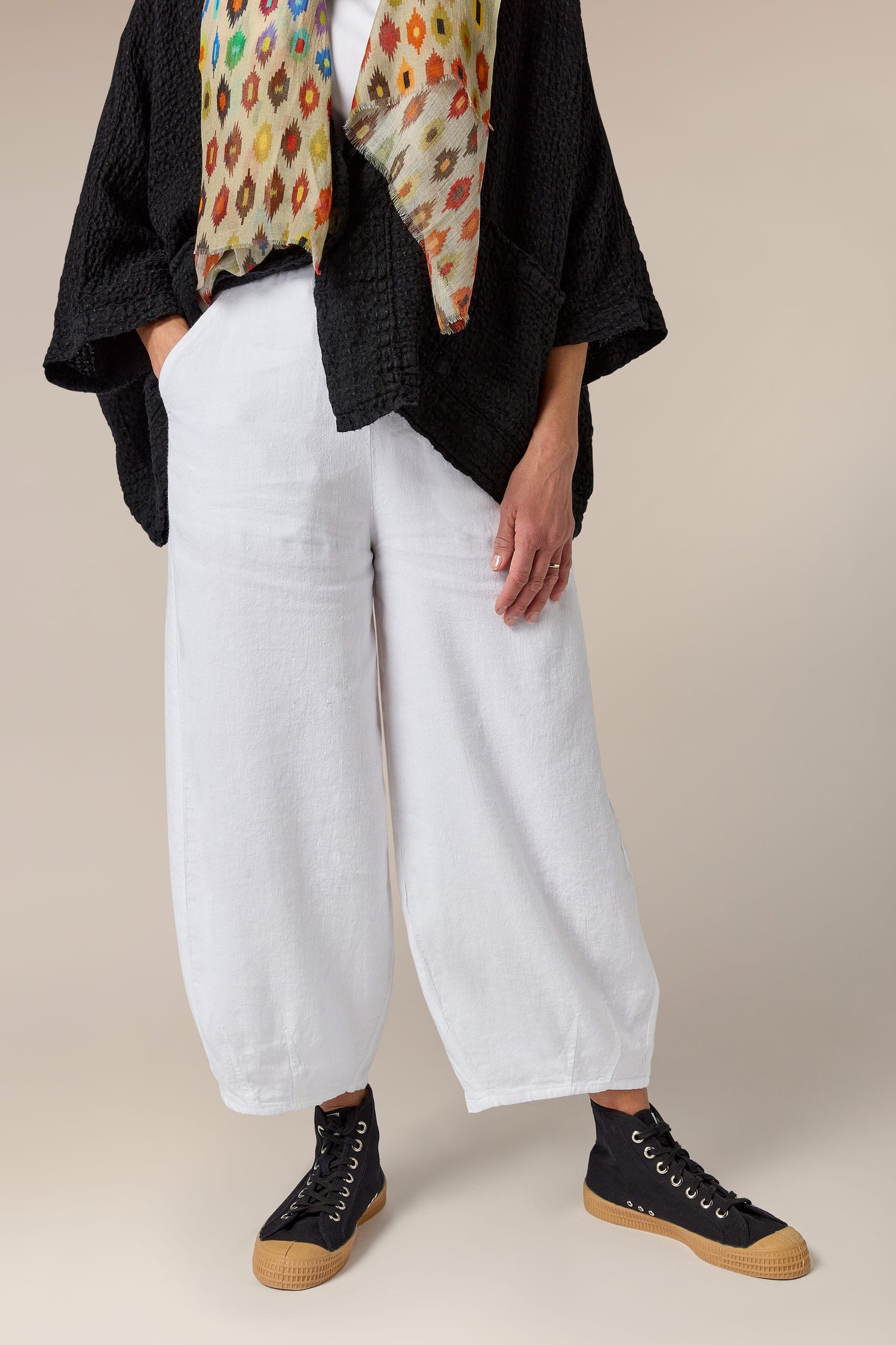 A woman in Twisted Linen Bubble Trousers, featuring side pockets.