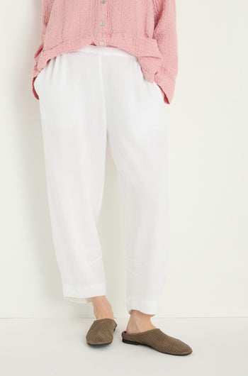 Person wearing a pink textured button-up shirt, Twisted Linen Crop Bubble Trouser with a breathable feel, and brown slip-on shoes, standing against a plain white background.