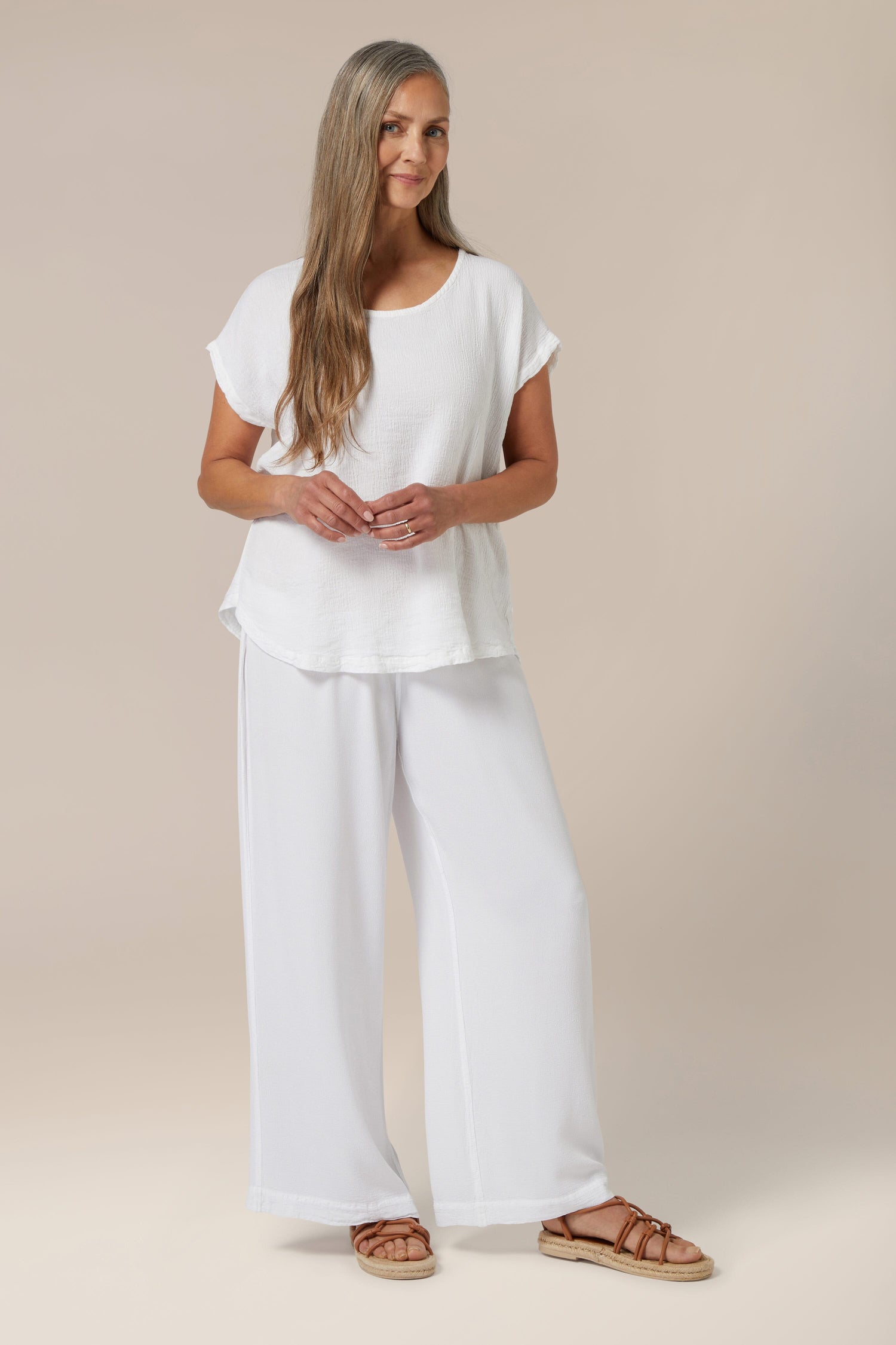 Woman posing in a white, lightweight Crinkle Linen Top summer outfit with sandals for a warm weather look.