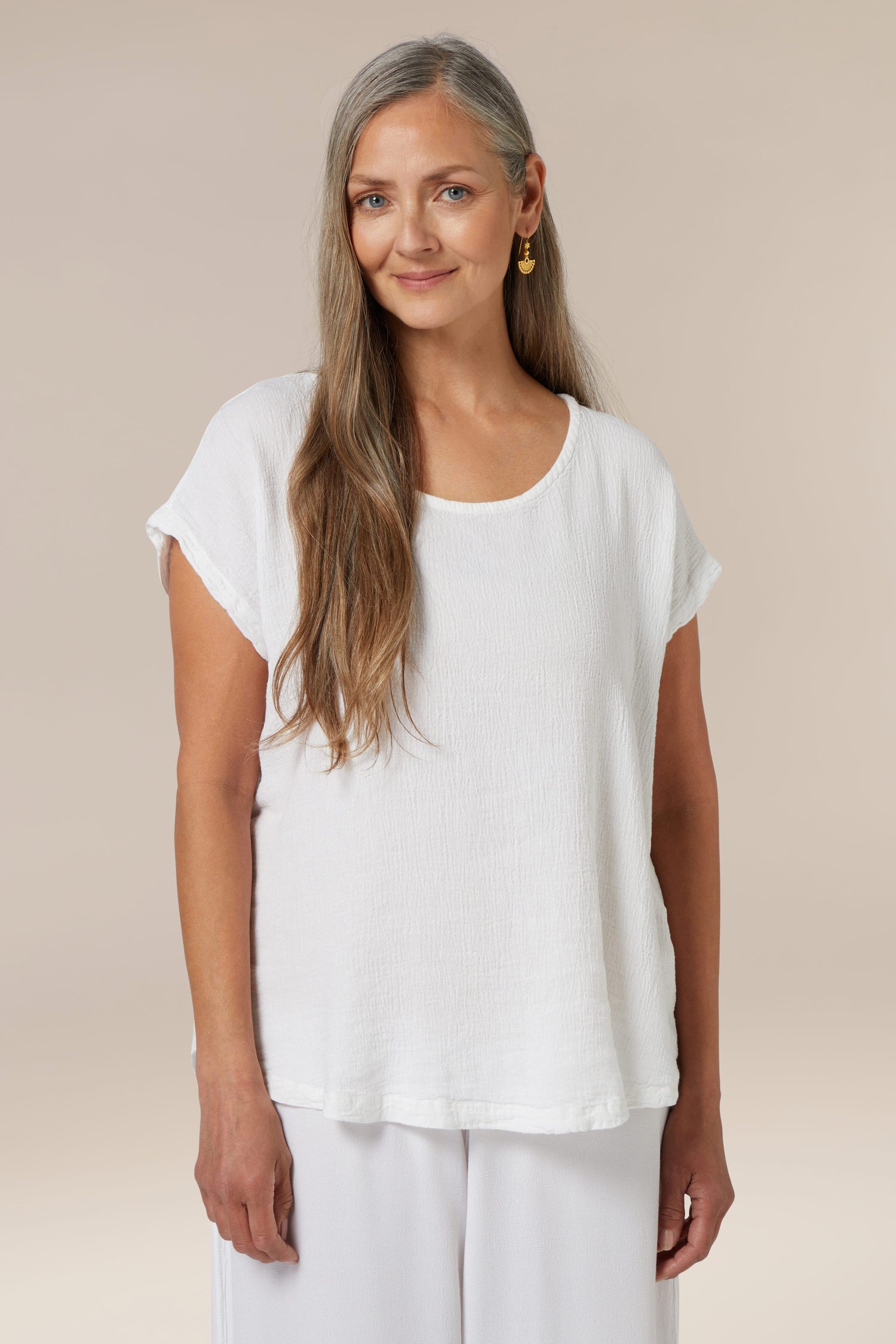 A woman with long gray hair wearing a Crinkle Linen Top and pants against a neutral background.