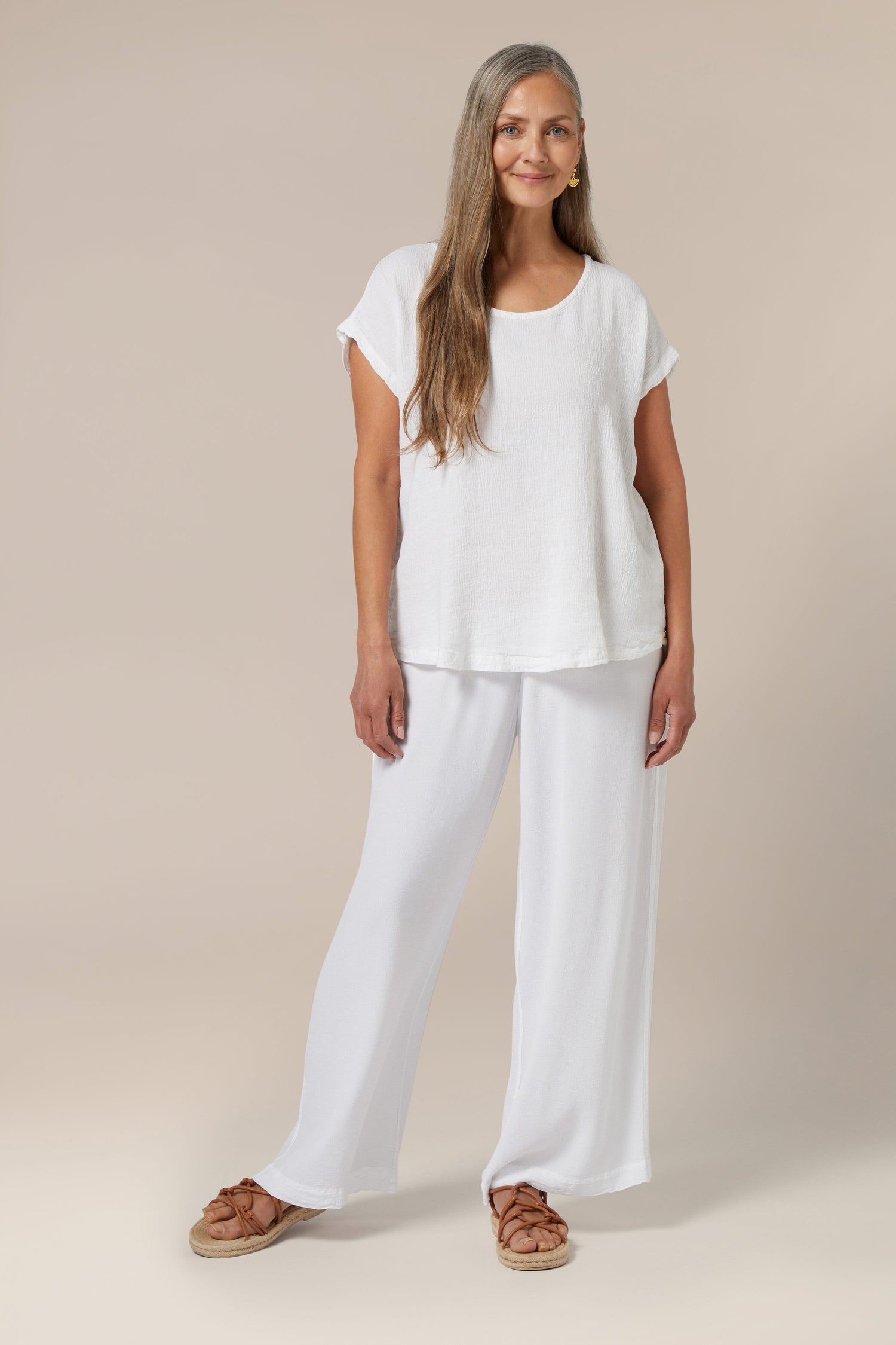 Sentence with product name: Woman in a Crinkle Linen Top standing against a neutral background for a warm weather look.
