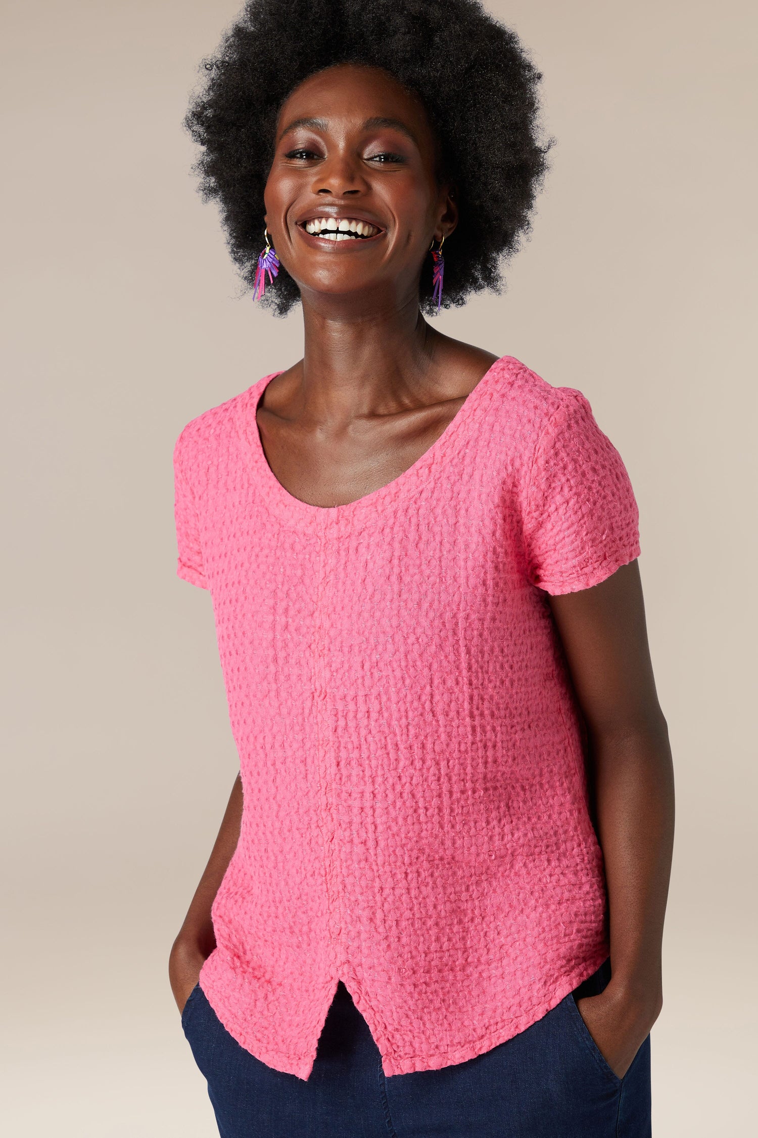 A woman wearing a soft Waffle Linen Top in pink and blue pants.