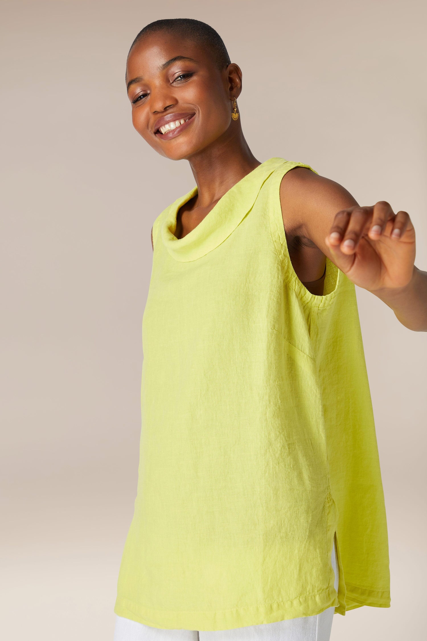A smiling black woman wearing an Organza Linen Cowl Vest, posing with one arm extended towards the camera.